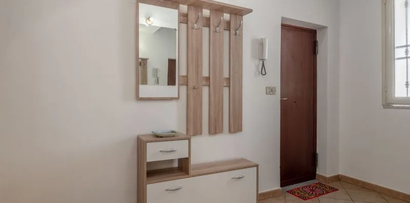 An entryway with a wooden coat rack, mirror, and small bench.