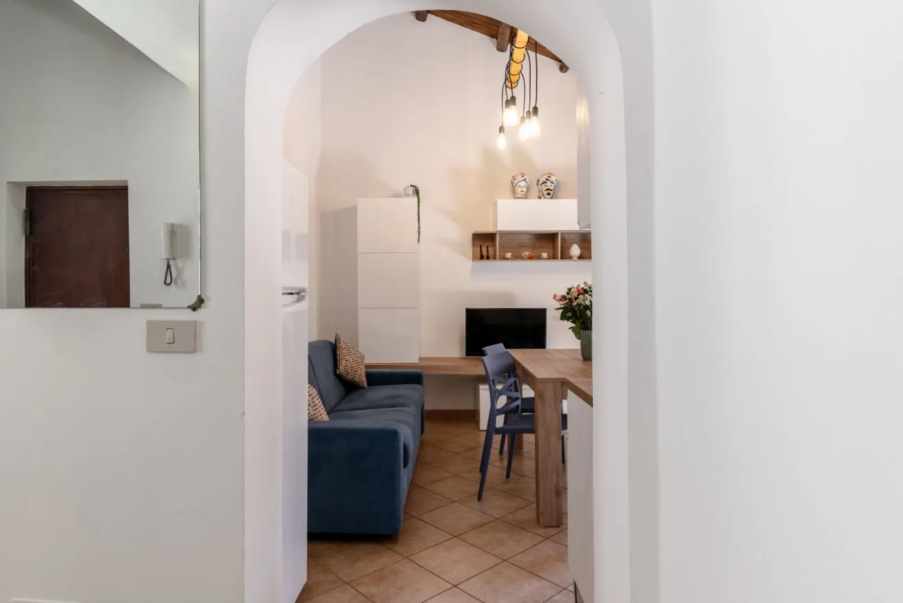 A dining and sitting area is visible through an arched opening, with a table and seating.