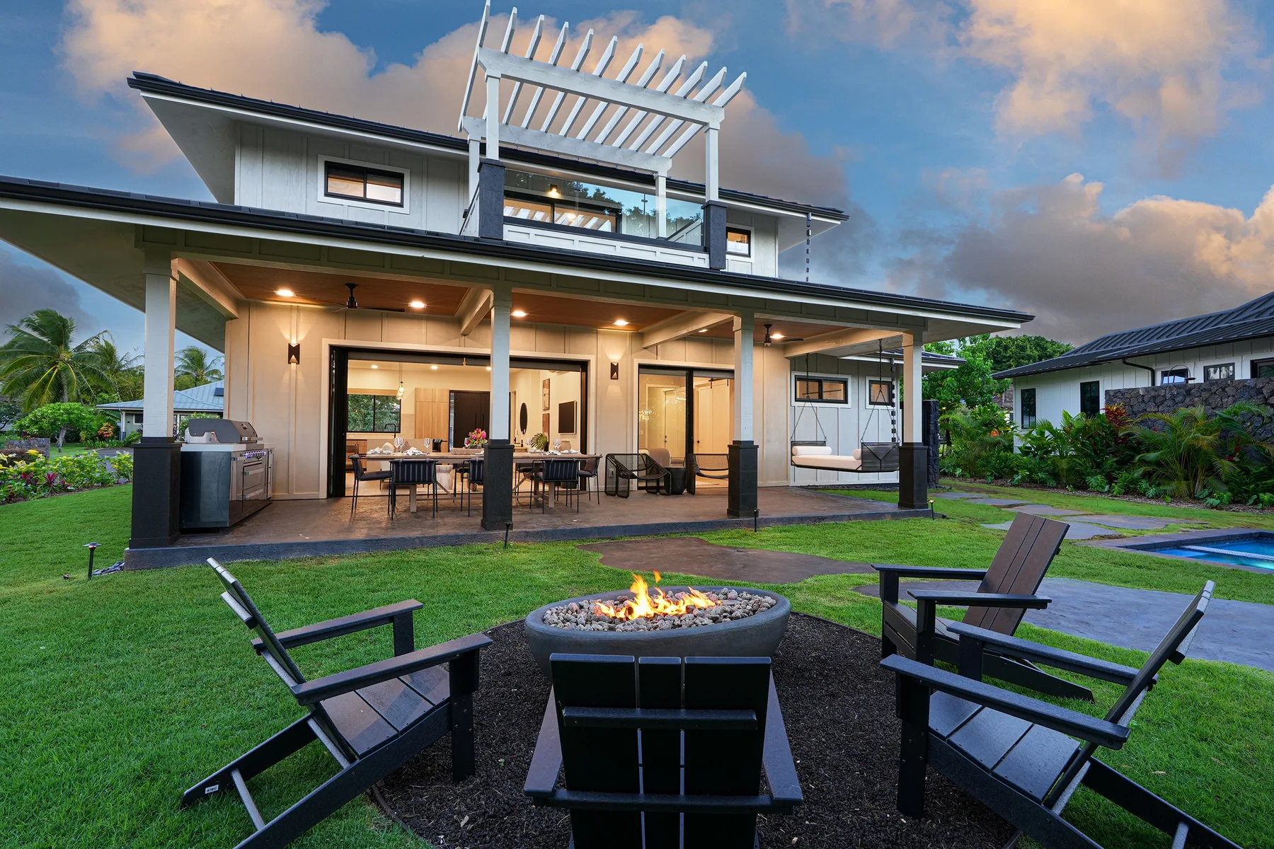 A backyard patio with outdoor seating and a fire pit in front of a house.