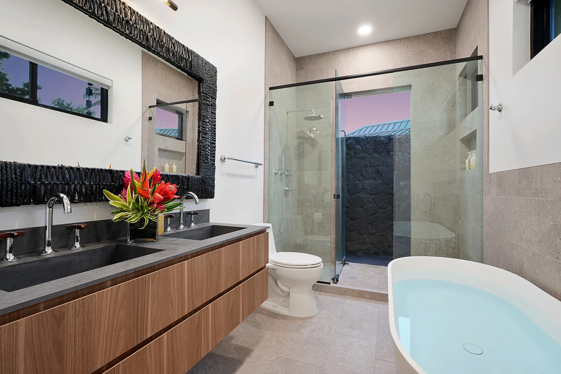 A modern bathroom with a double sink, glass shower, and soaking tub.