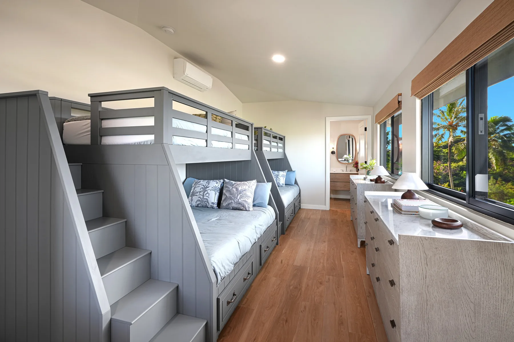 A bedroom with built-in bunk beds and a long desk beneath the windows.