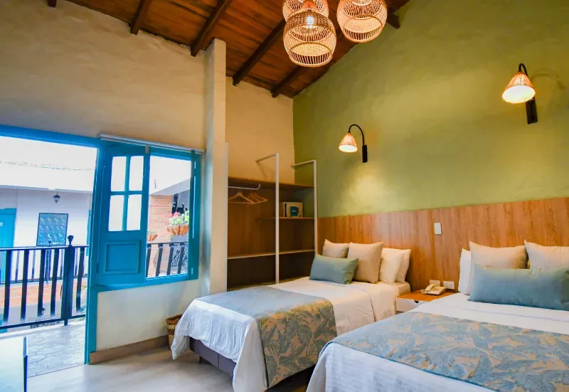 Habitación con dos camas y una puerta azul que da a un balcón.