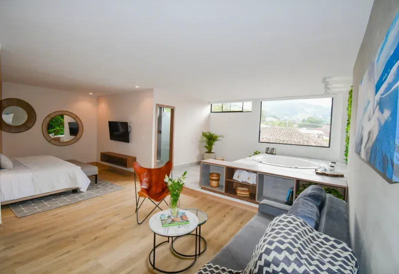 Habitación con cama, sofá, bañera y ventana grande.