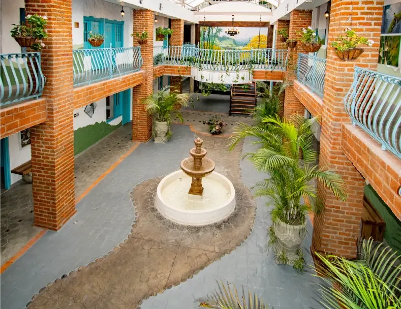 Patio interior con fuente central, balcones y plantas.