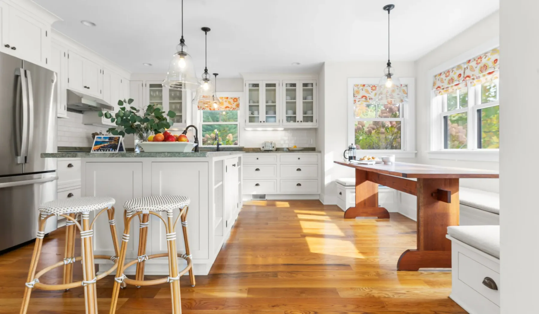 Una cocina luminosa con una isla central y una mesa de comedor de madera.