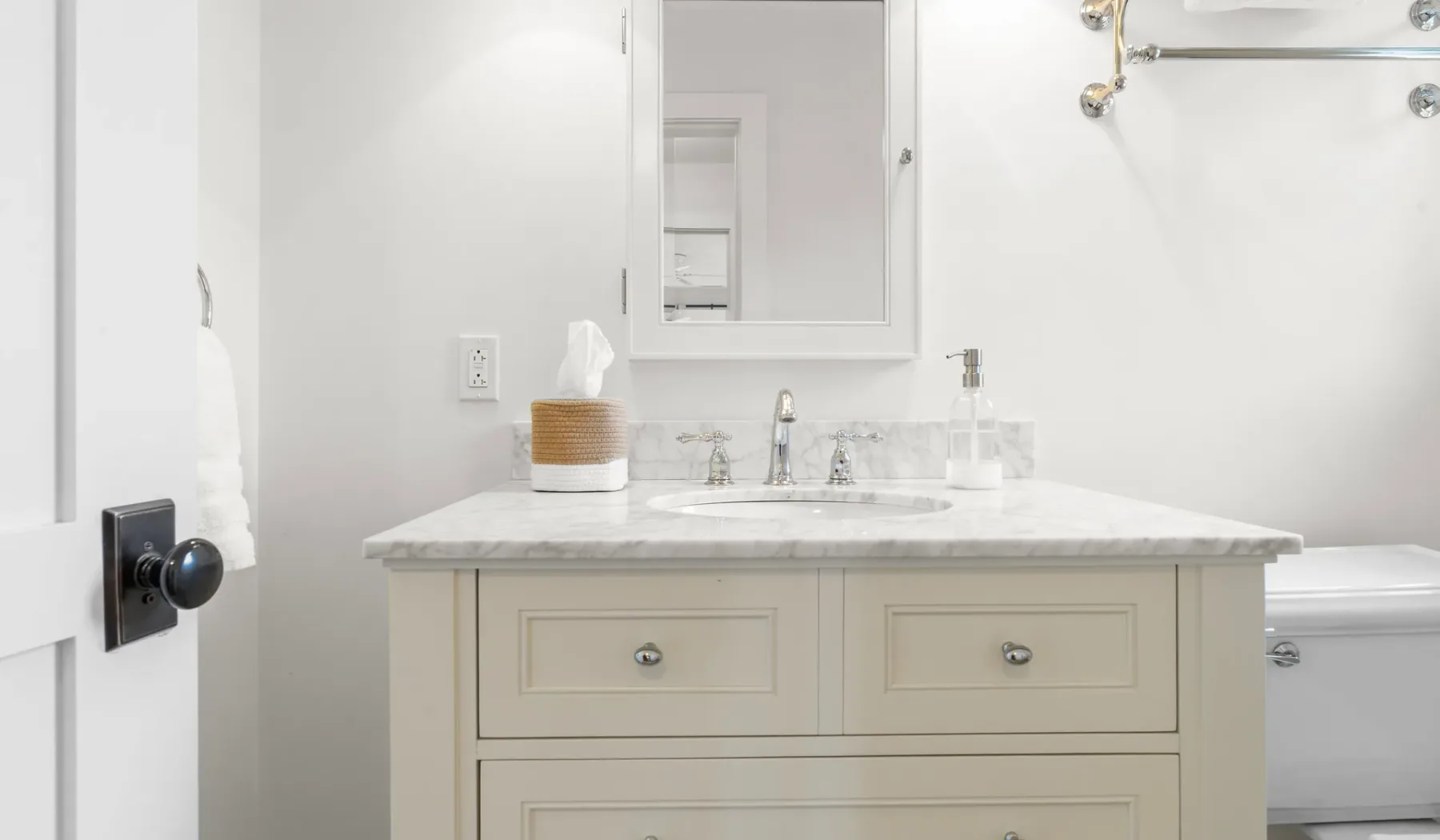 Un tocador de baño luminoso con un espejo y una bañera al lado.