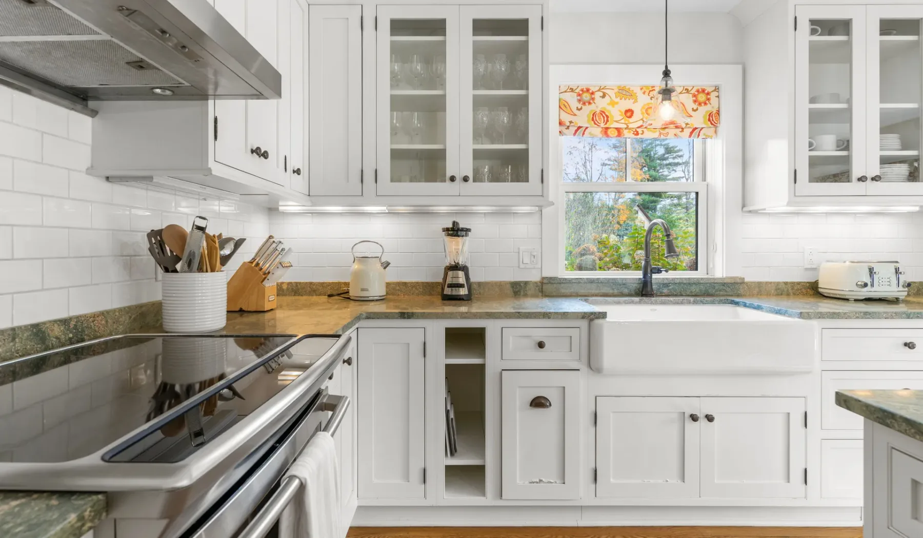 Una cocina blanca y luminosa, con un fregadero amplio y una ventana sobre la encimera.