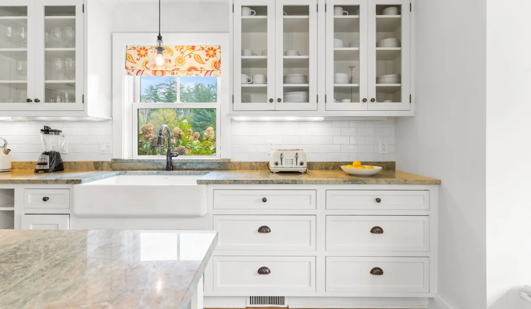 Una cocina luminosa con gabinetes blancos, una encimera y una ventana sobre el fregadero.