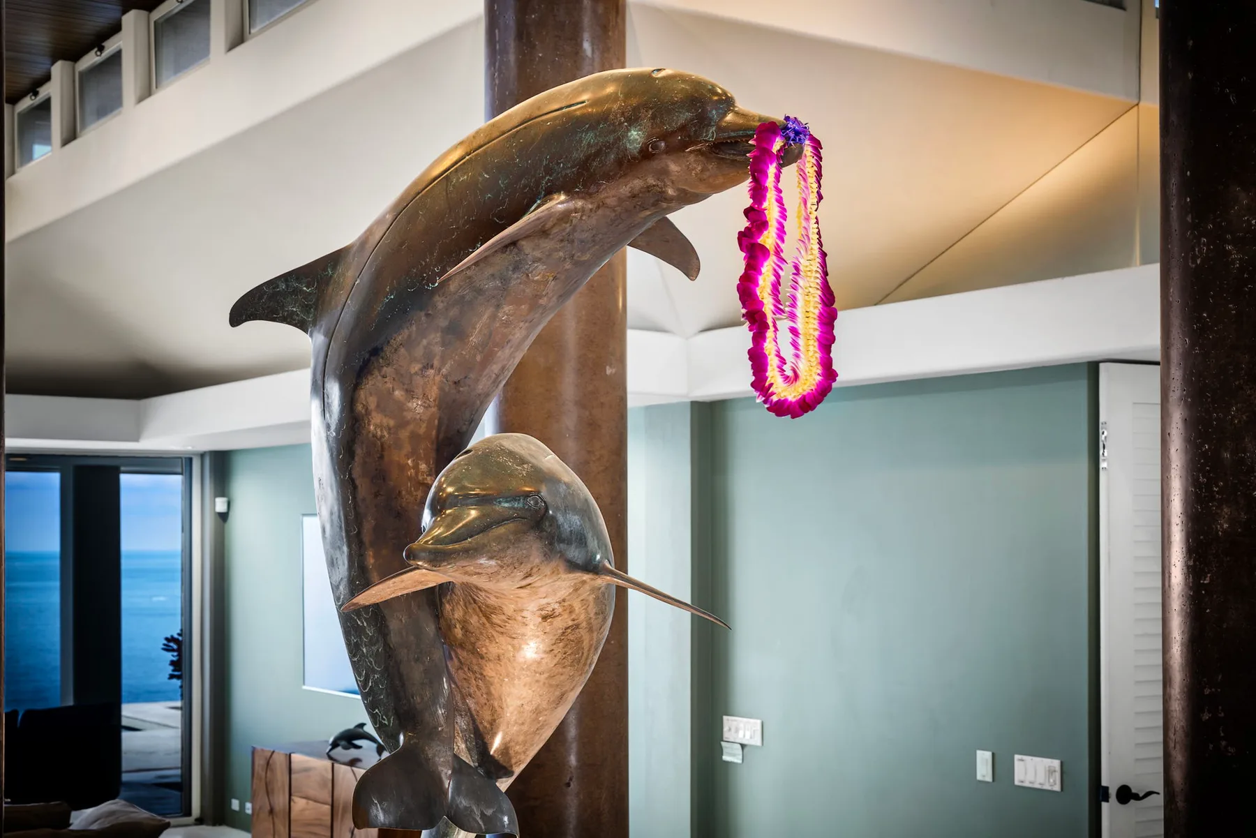 Una gran escultura de delfines está en el interior junto a una guirnalda floral colorida.