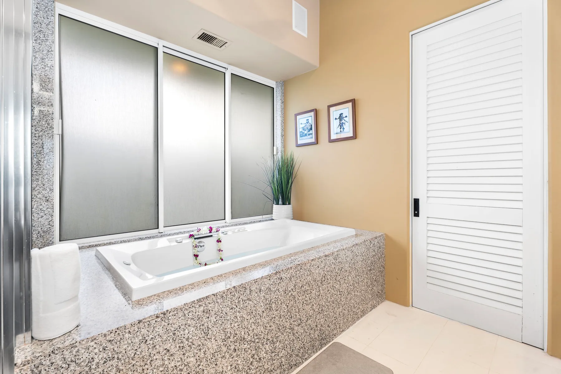 Un baño con una bañera empotrada bajo ventanas esmeriladas.