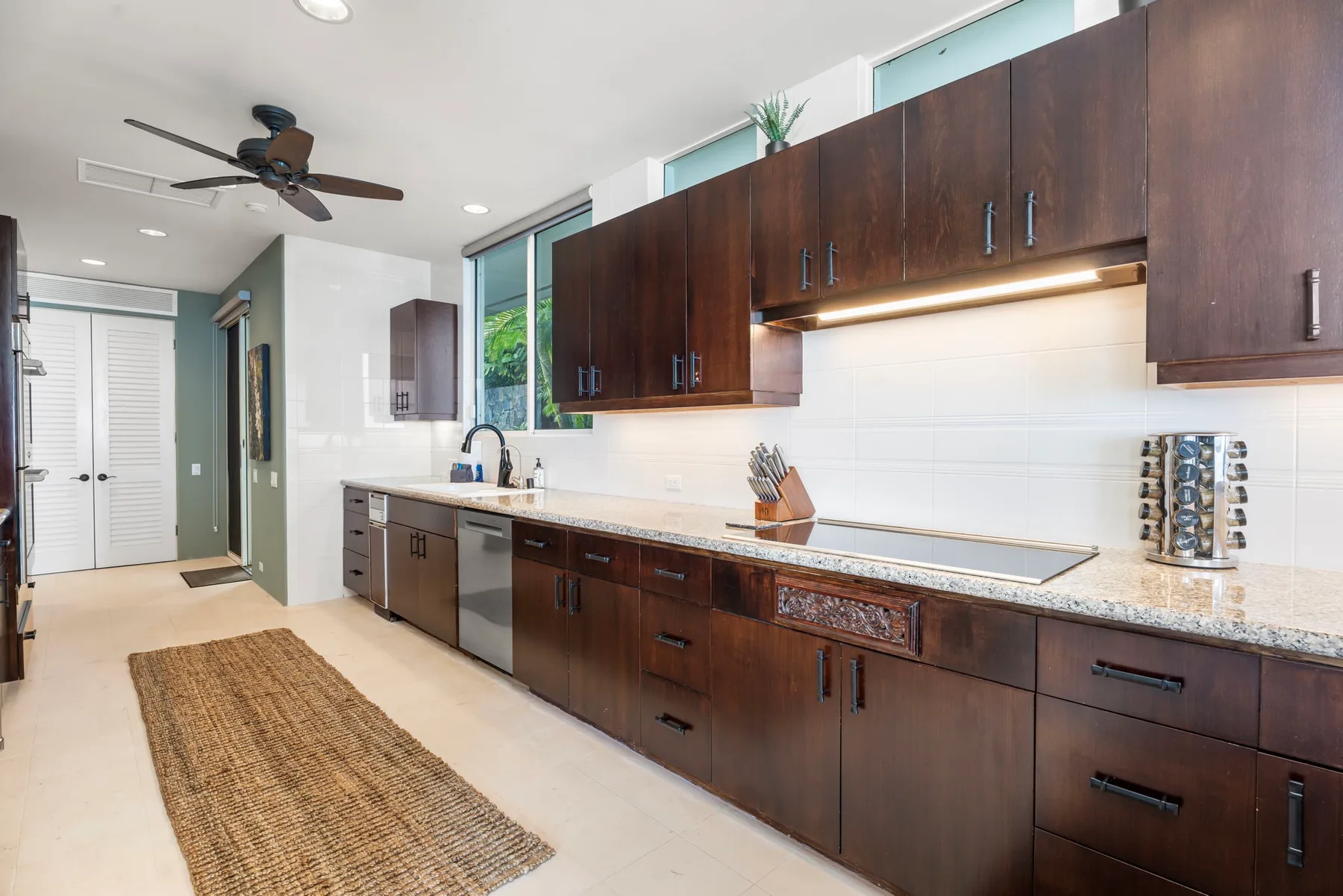 Una cocina moderna con gabinetes de madera oscura, una encimera larga y un ventilador de techo.