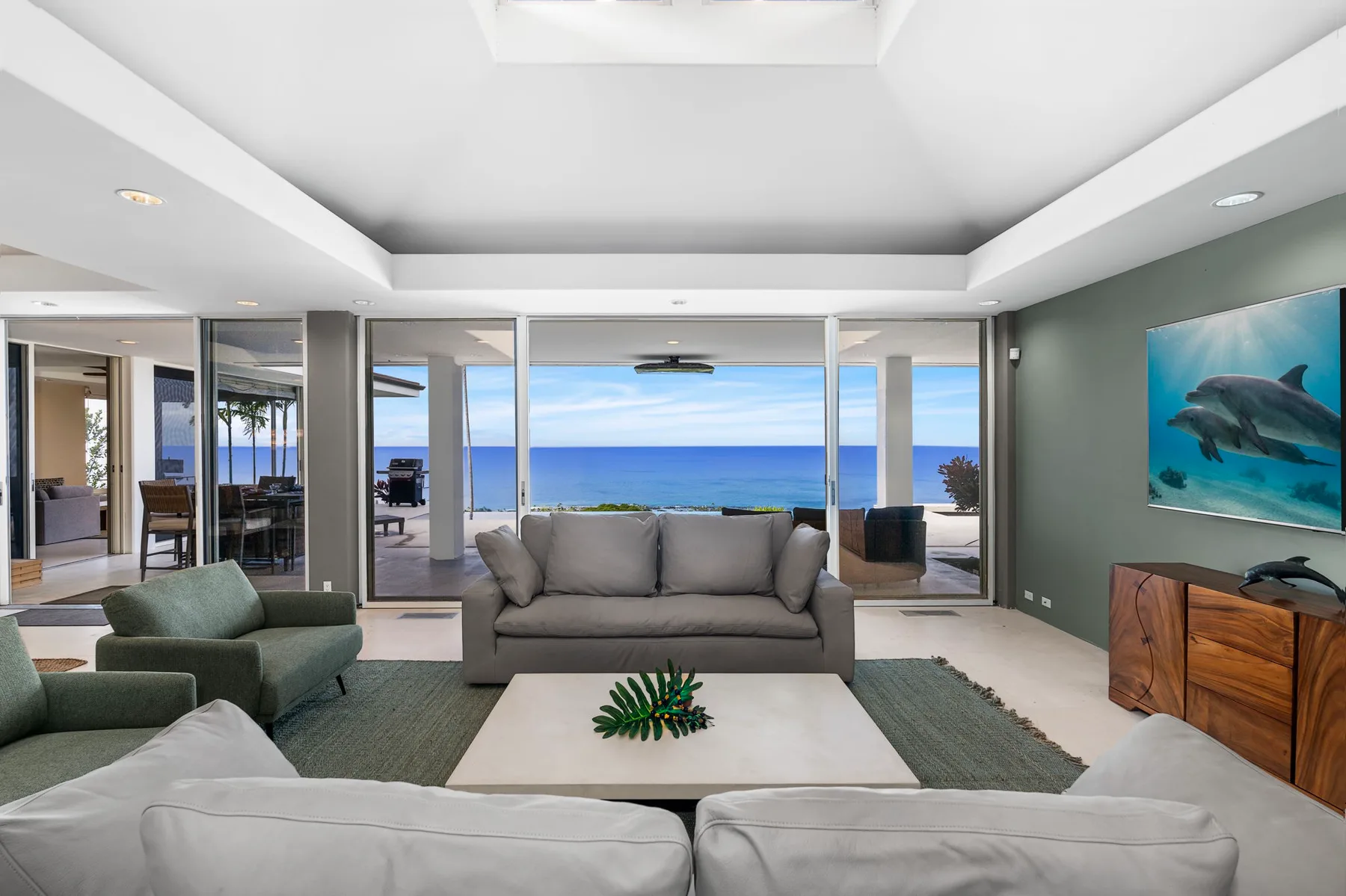 Una sala de estar con asientos frente a grandes ventanas con vista al océano.
