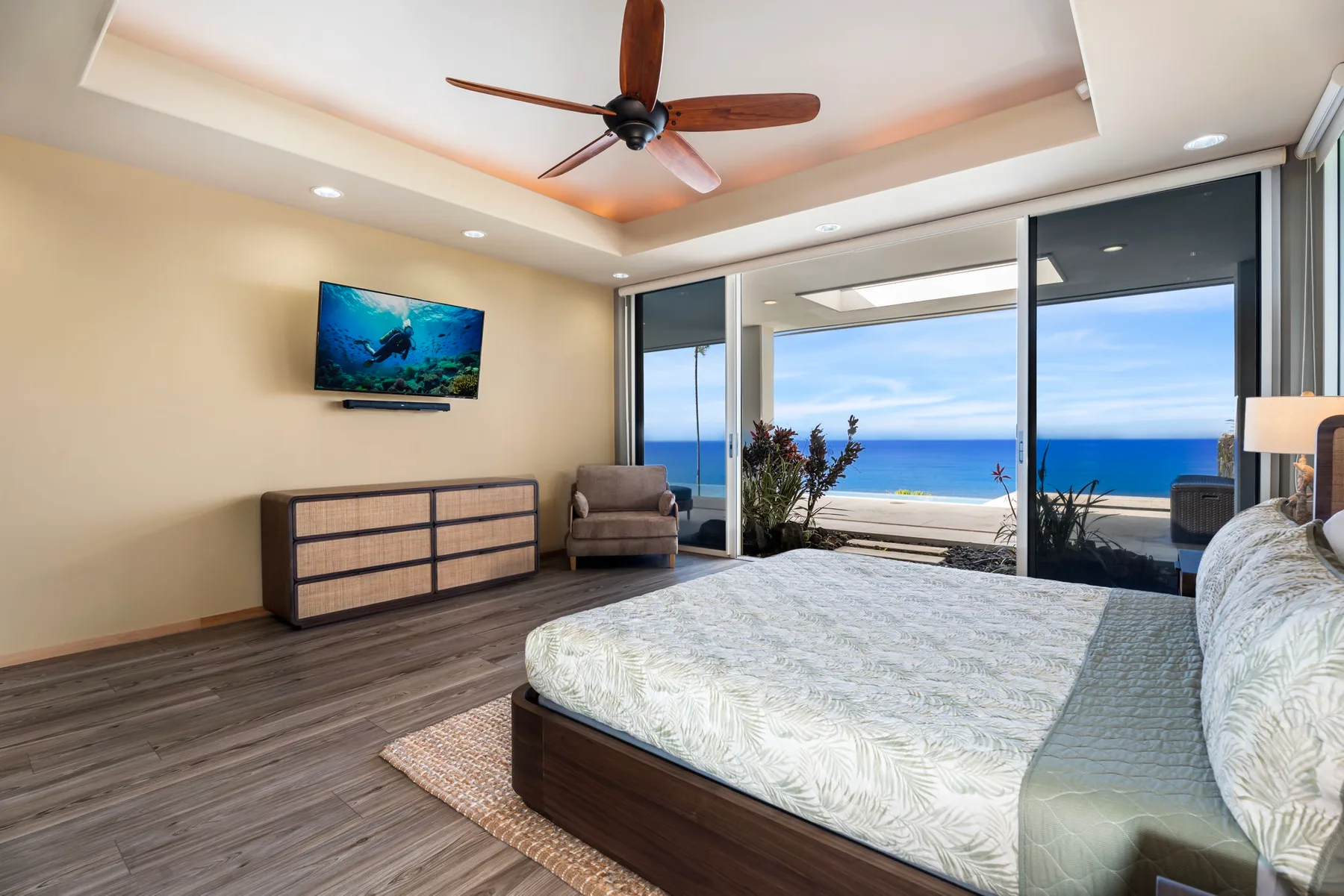 Un dormitorio con una cama grande y puertas corredizas de vidrio con vista al mar.