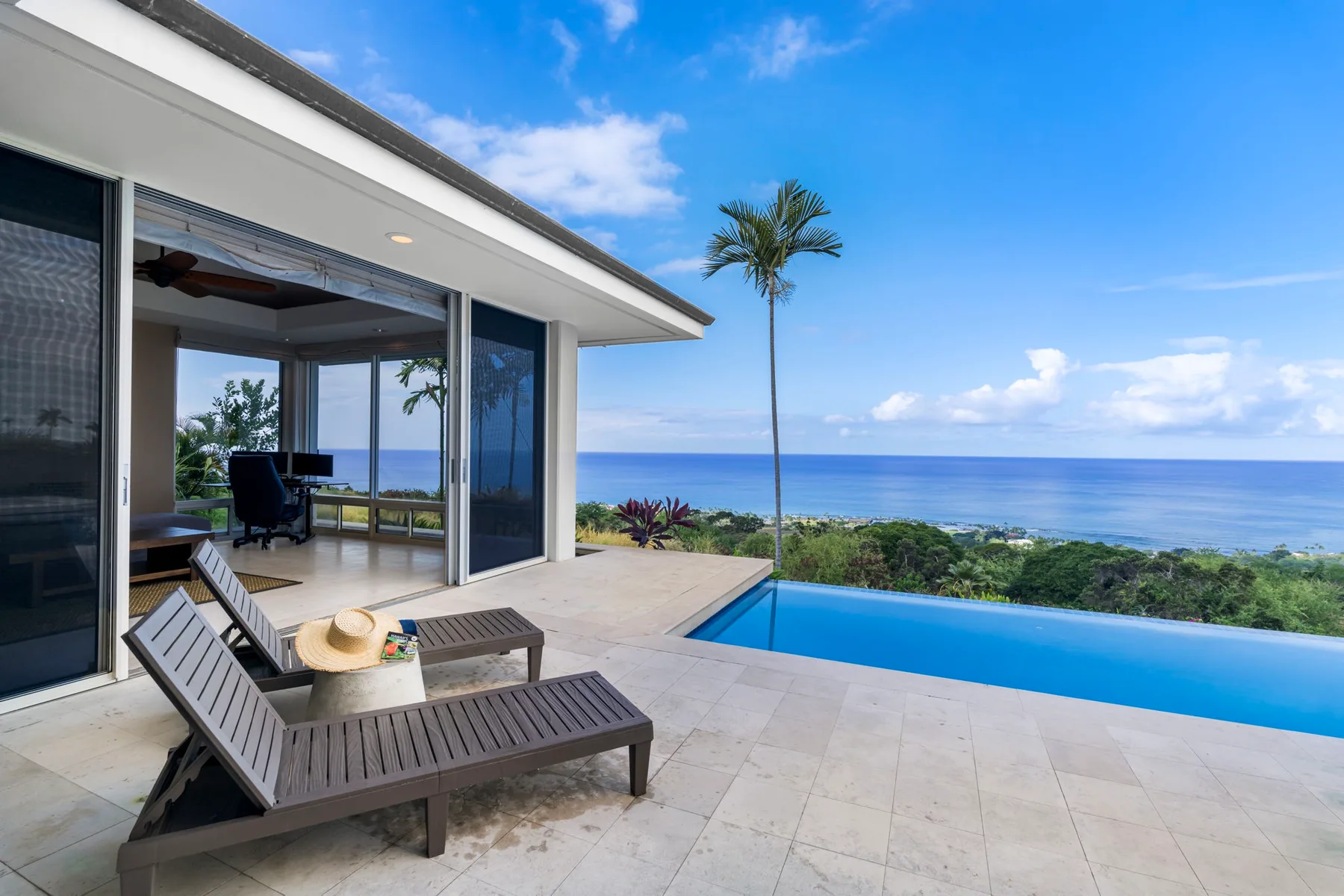 Un patio junto al mar con asientos de descanso mira a una piscina y al océano.