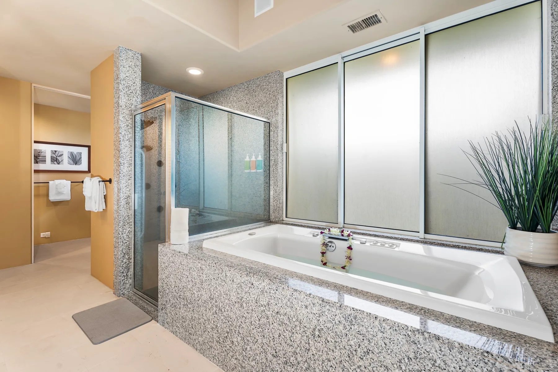 Un baño con bañera, ducha de vidrio y grandes ventanas esmeriladas.
