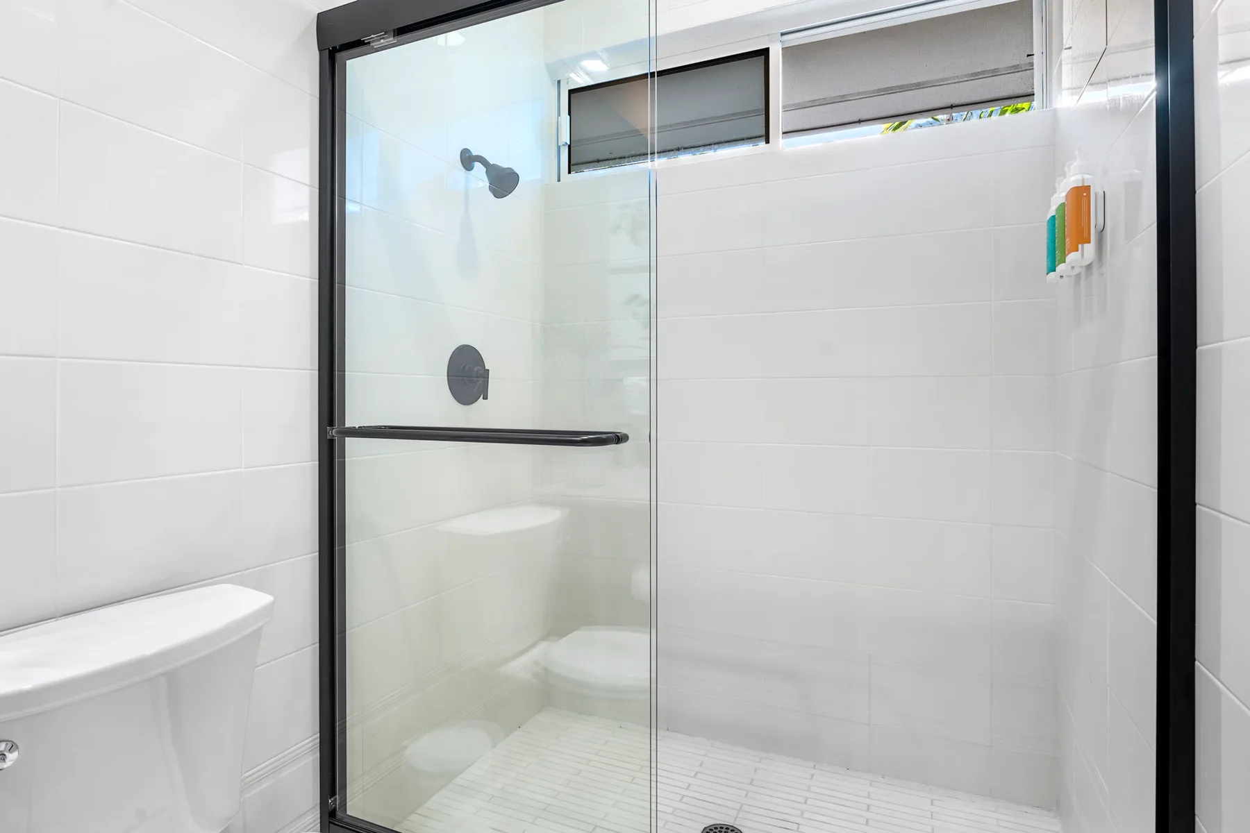 Un baño alicatado con una ducha de vidrio y controles en la pared.