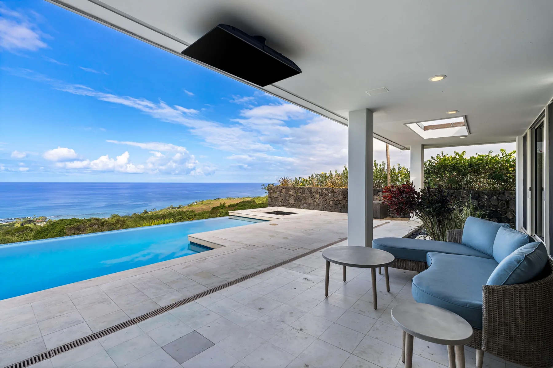 Una sala exterior cubierta junto a una piscina ofrece vistas al océano.