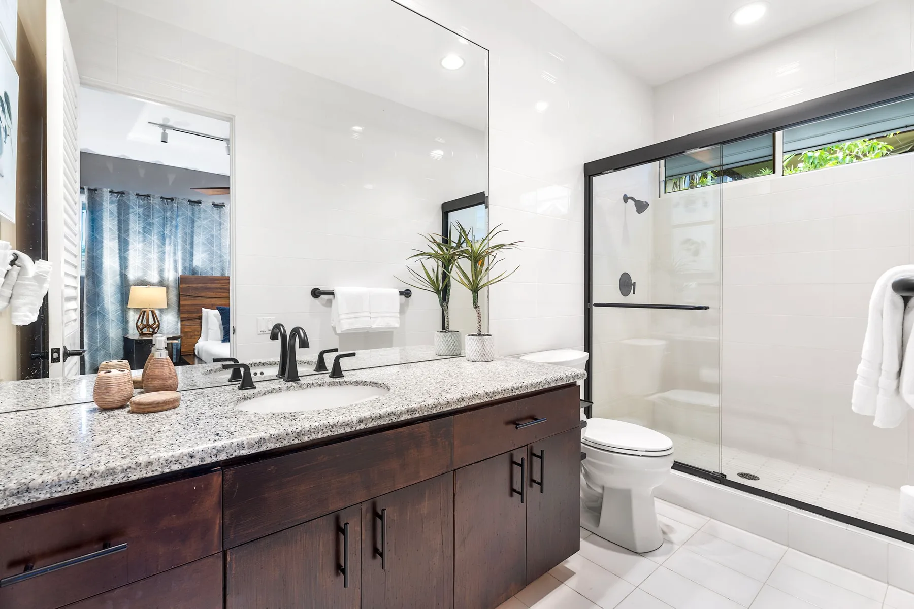 Un baño luminoso con un mueble largo, dos lavabos y una ducha de vidrio.