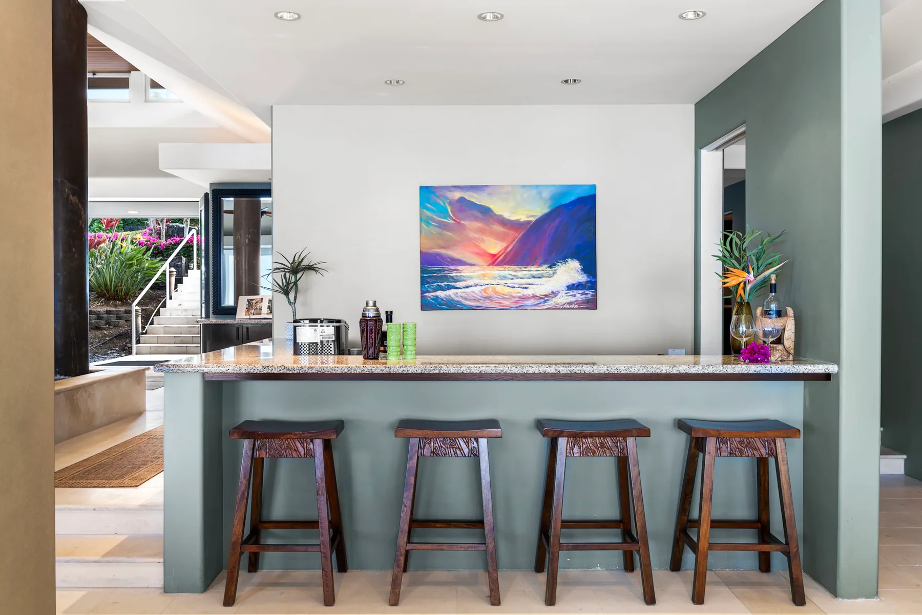 Una zona de bar moderna con taburetes de madera y un cuadro colorido de paisaje.