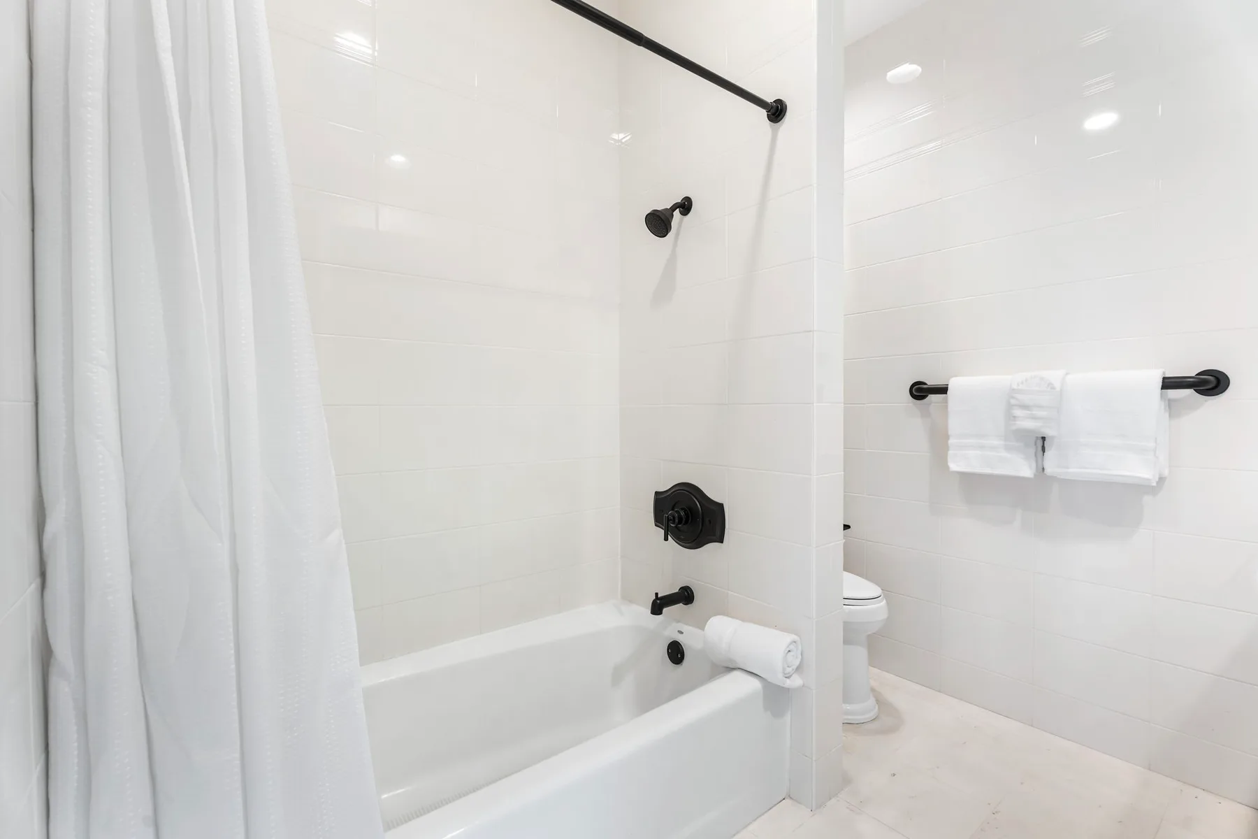 Un baño con bañera, ducha y toallas colgadas en una barra de pared.