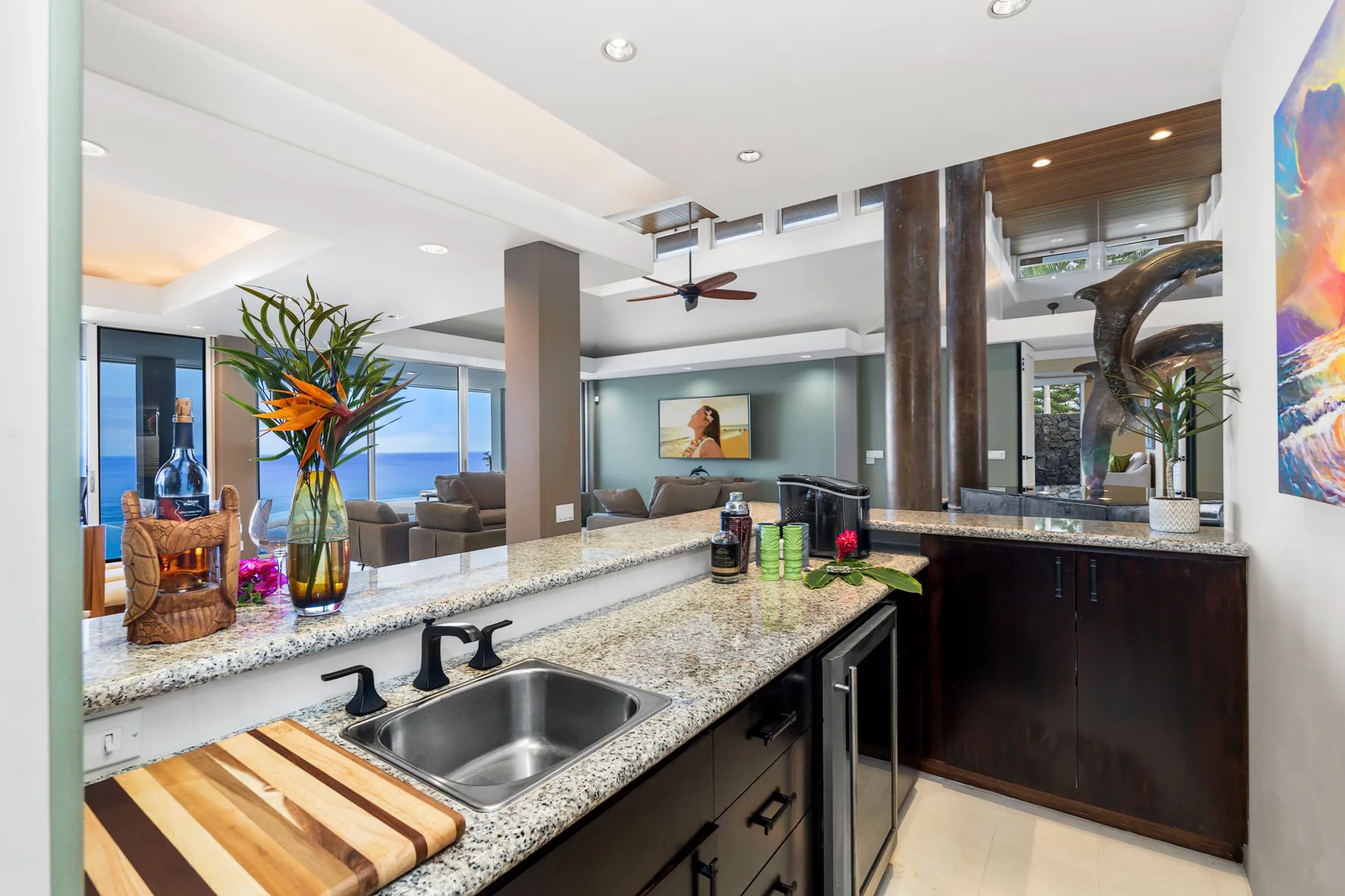 Una cocina moderna con una isla de granito y una sala de estar abierta al fondo.