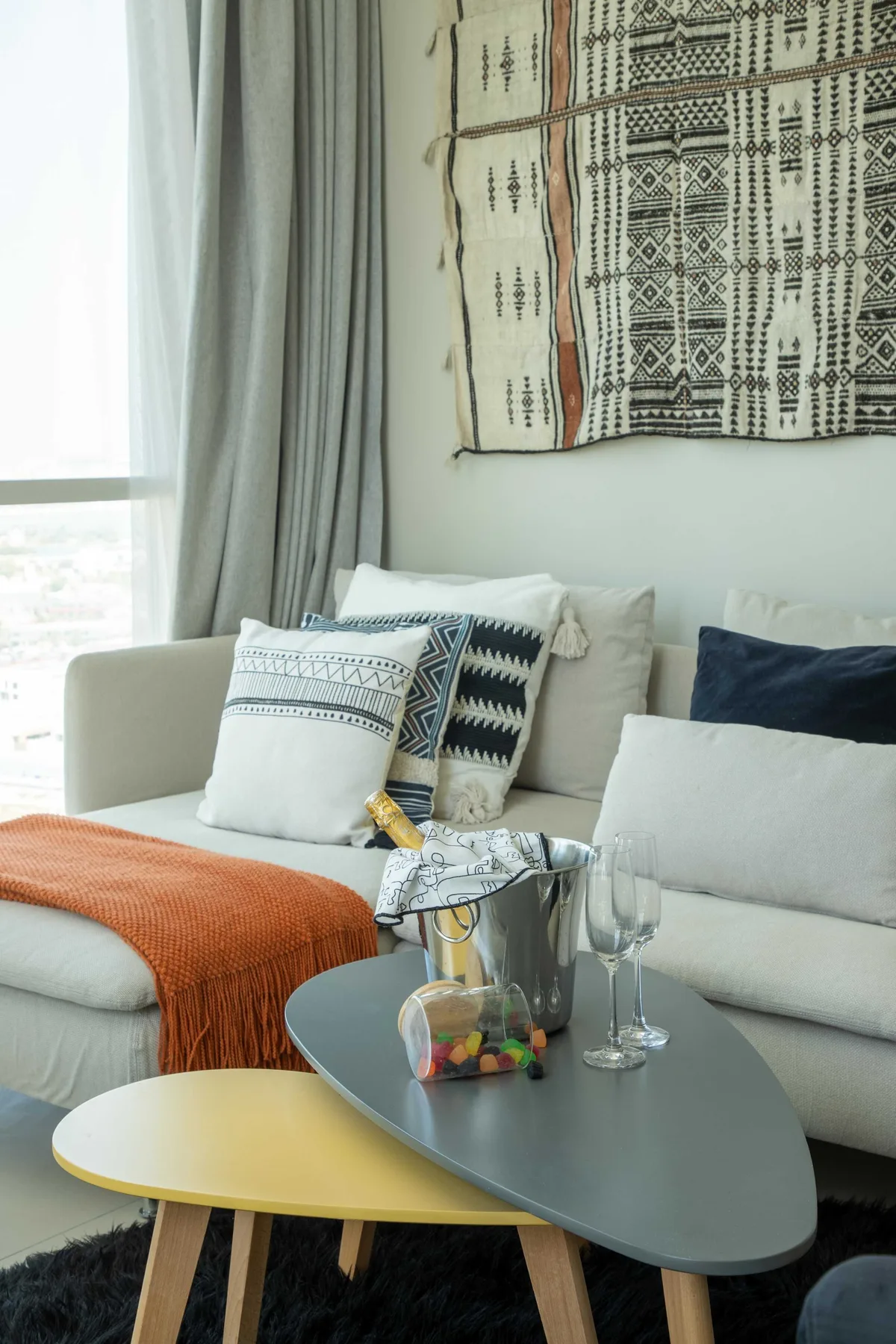 Una sala luminosa con un sofá claro, cojines estampados y una mesa baja.