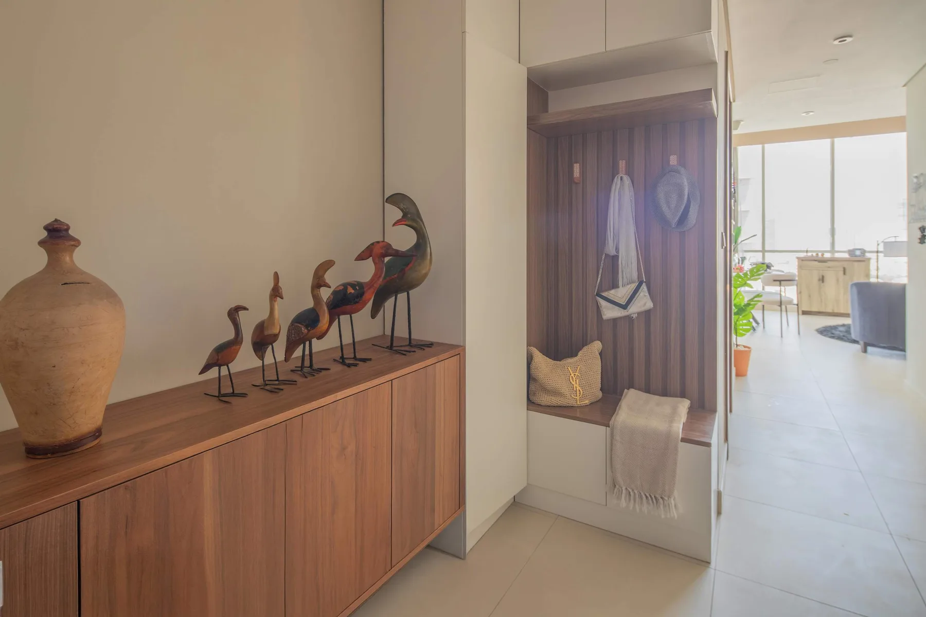 Una consola en el pasillo exhibe cerámica decorativa y figuras de aves junto a un rincón empotrado para sentarse.