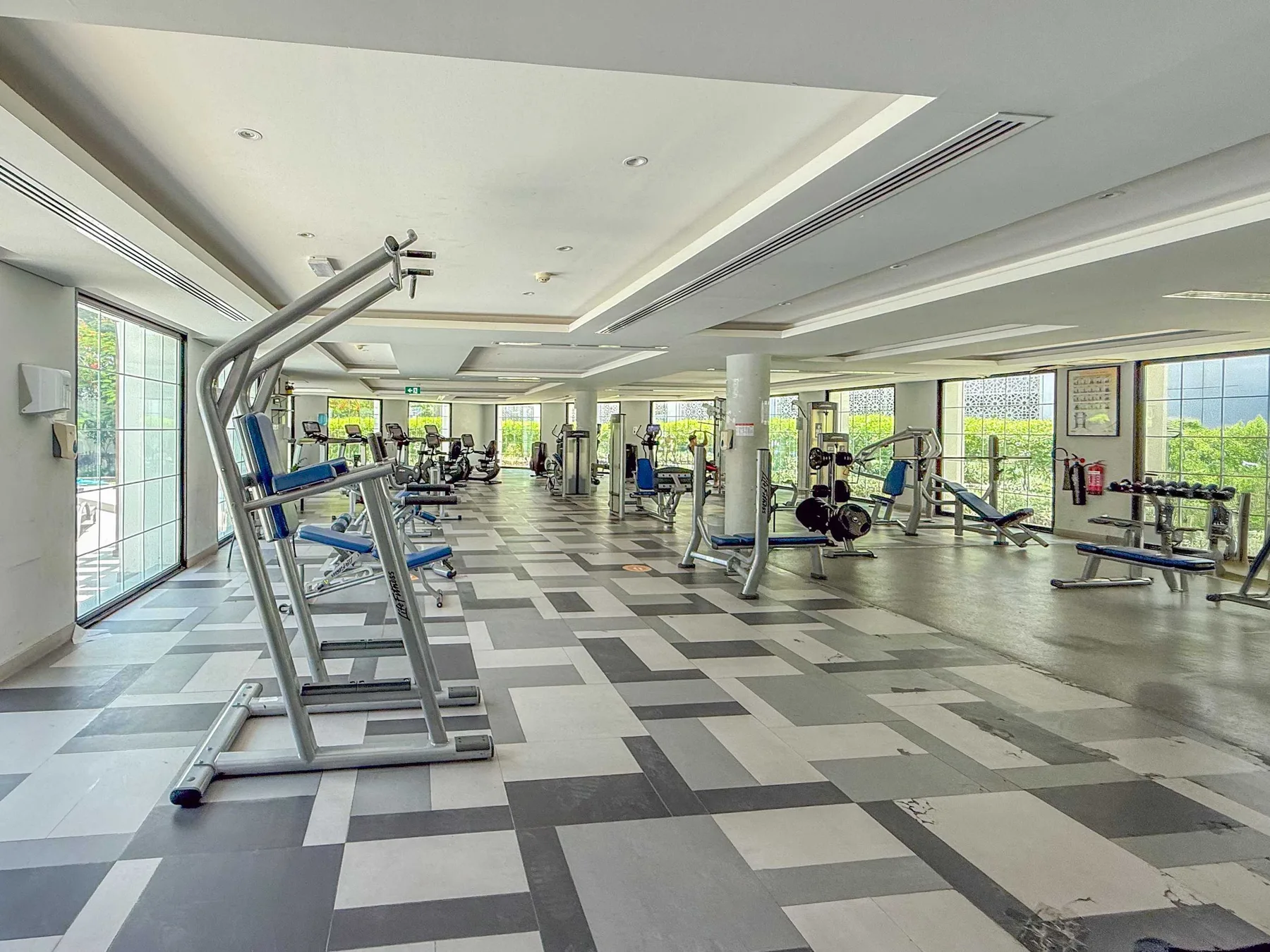 Un gimnasio amplio con máquinas de ejercicio y grandes ventanas.