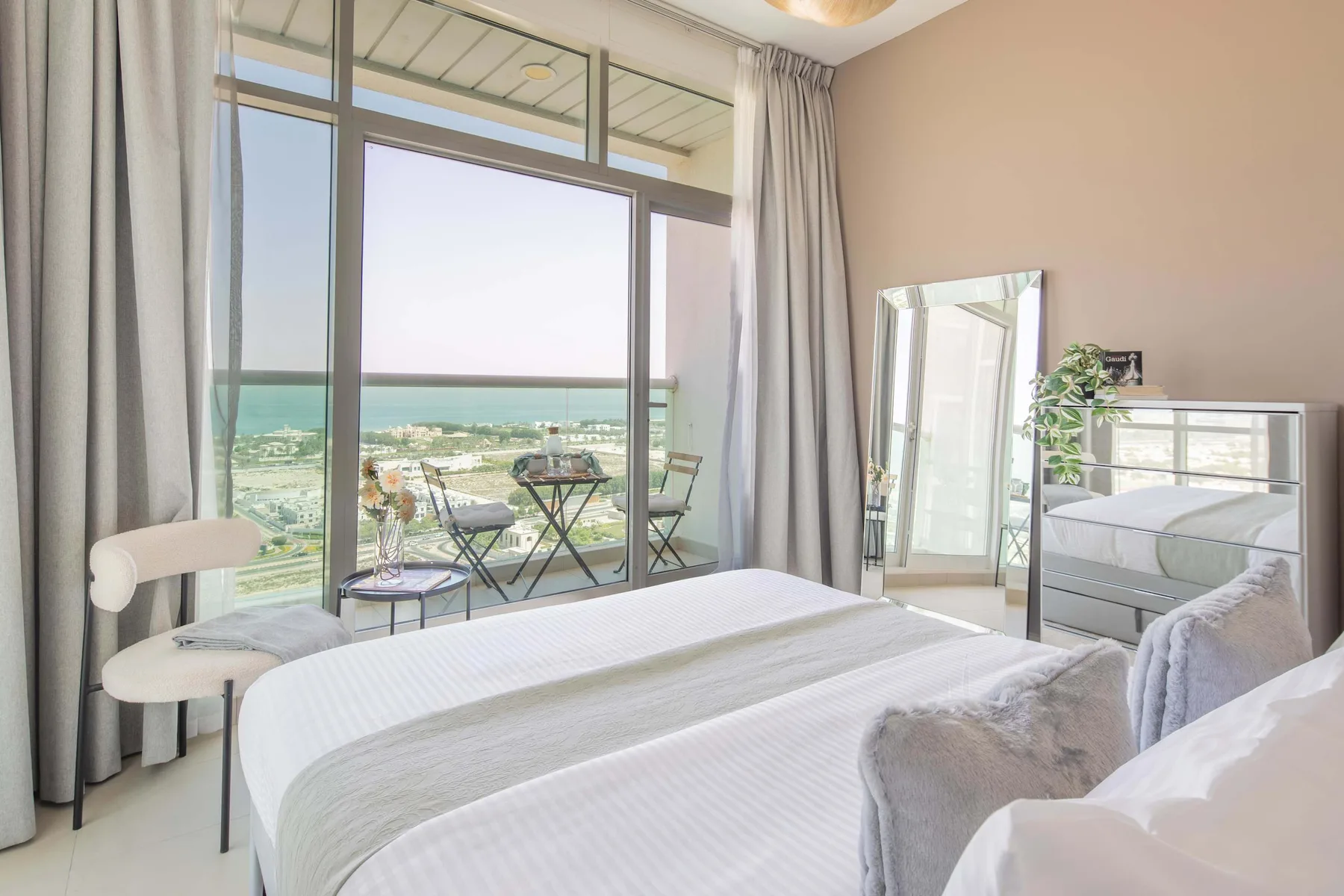 Un dormitorio luminoso con camas junto a grandes ventanales con vistas al paisaje.