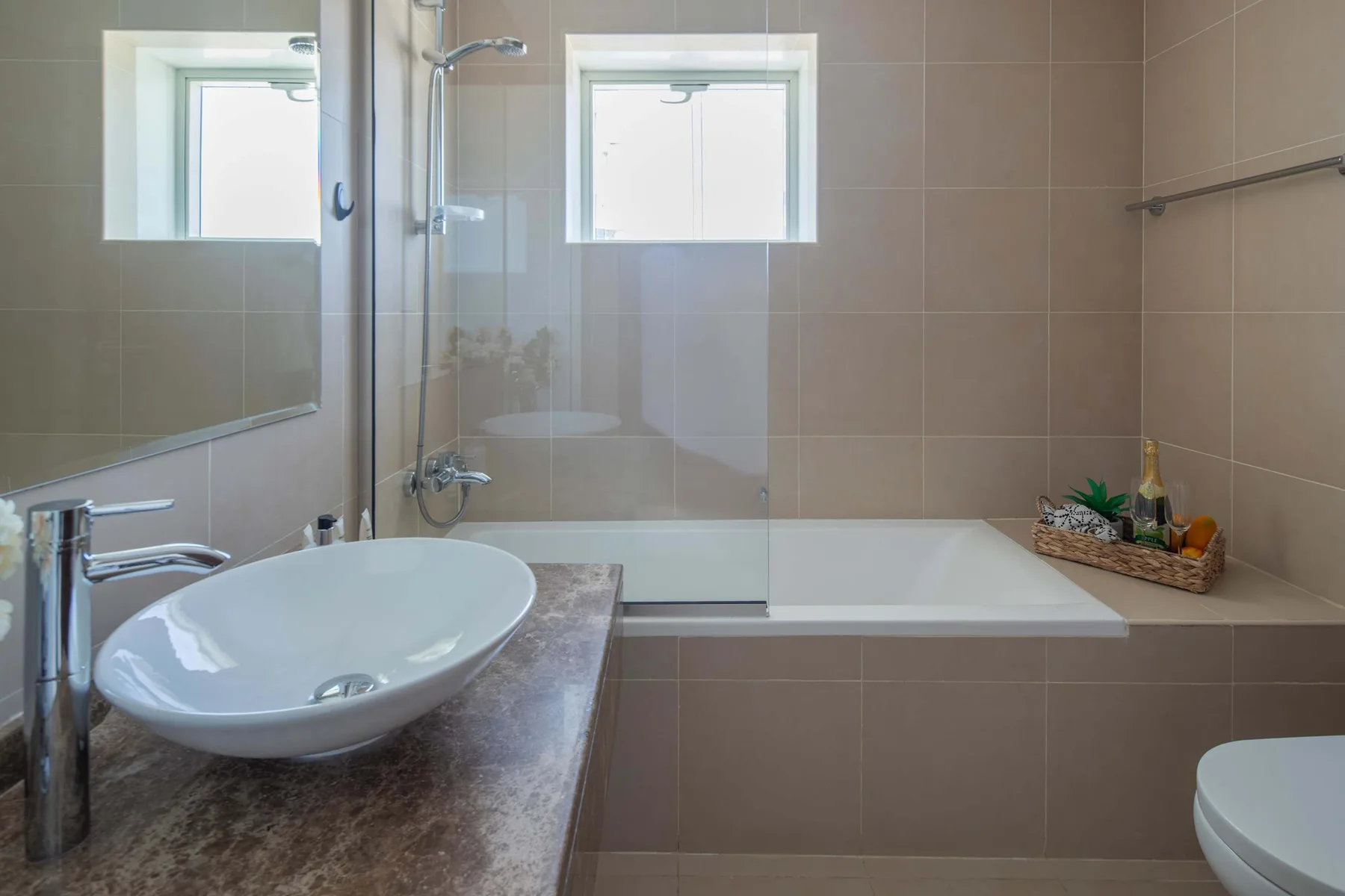 Un baño con bañera, mampara de ducha de vidrio y lavabo.
