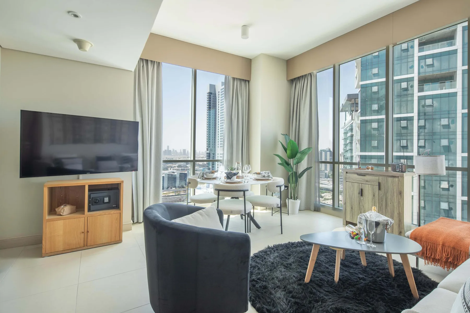 Una sala luminosa con asientos, una mesa de comedor y ventanas de piso a techo.