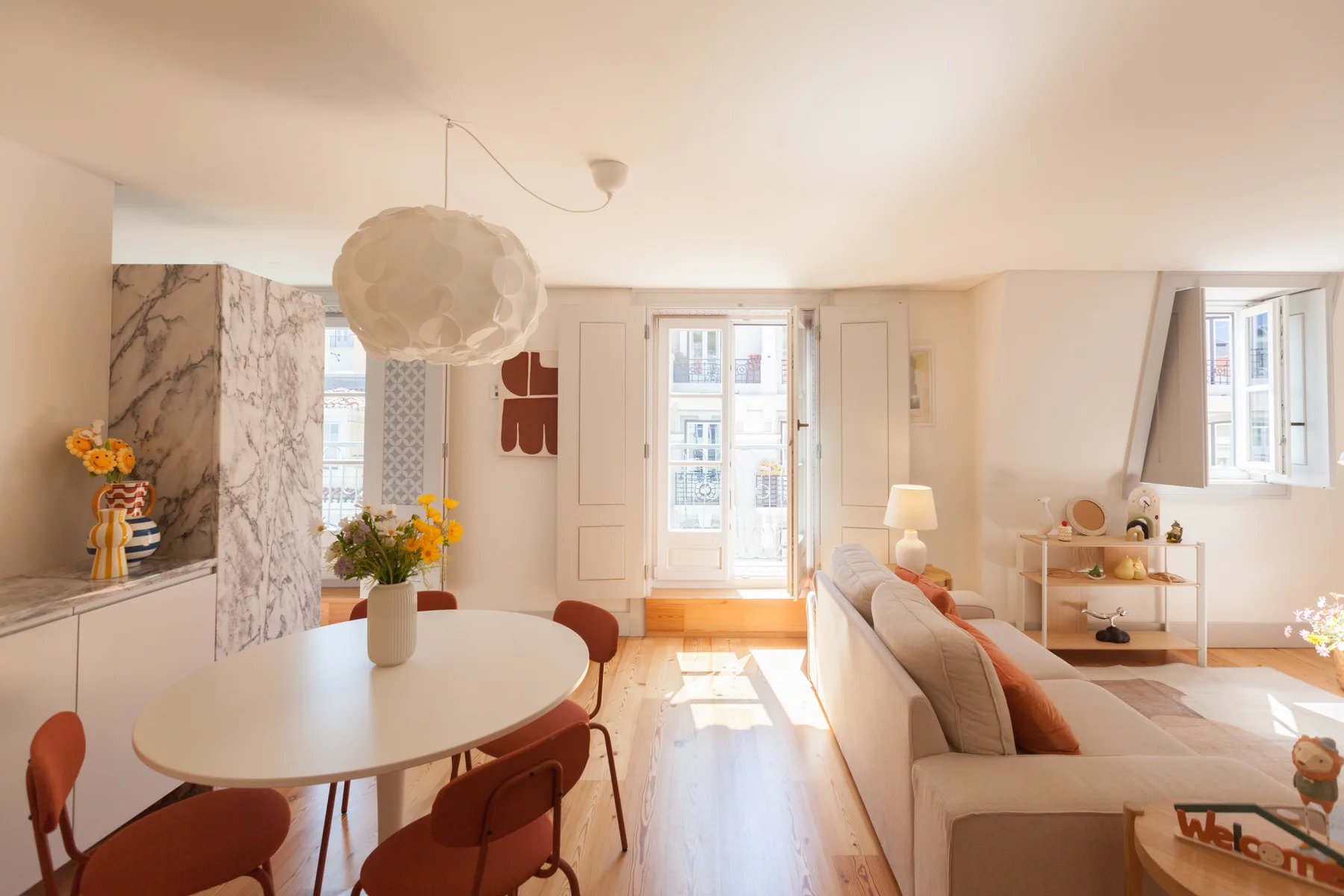 A bright living and dining area with a table, seating, and tall windows.
