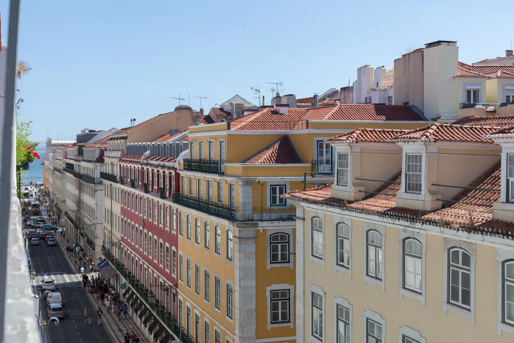 A row of colorful buildings lines a narrow city street beneath a clear sky.