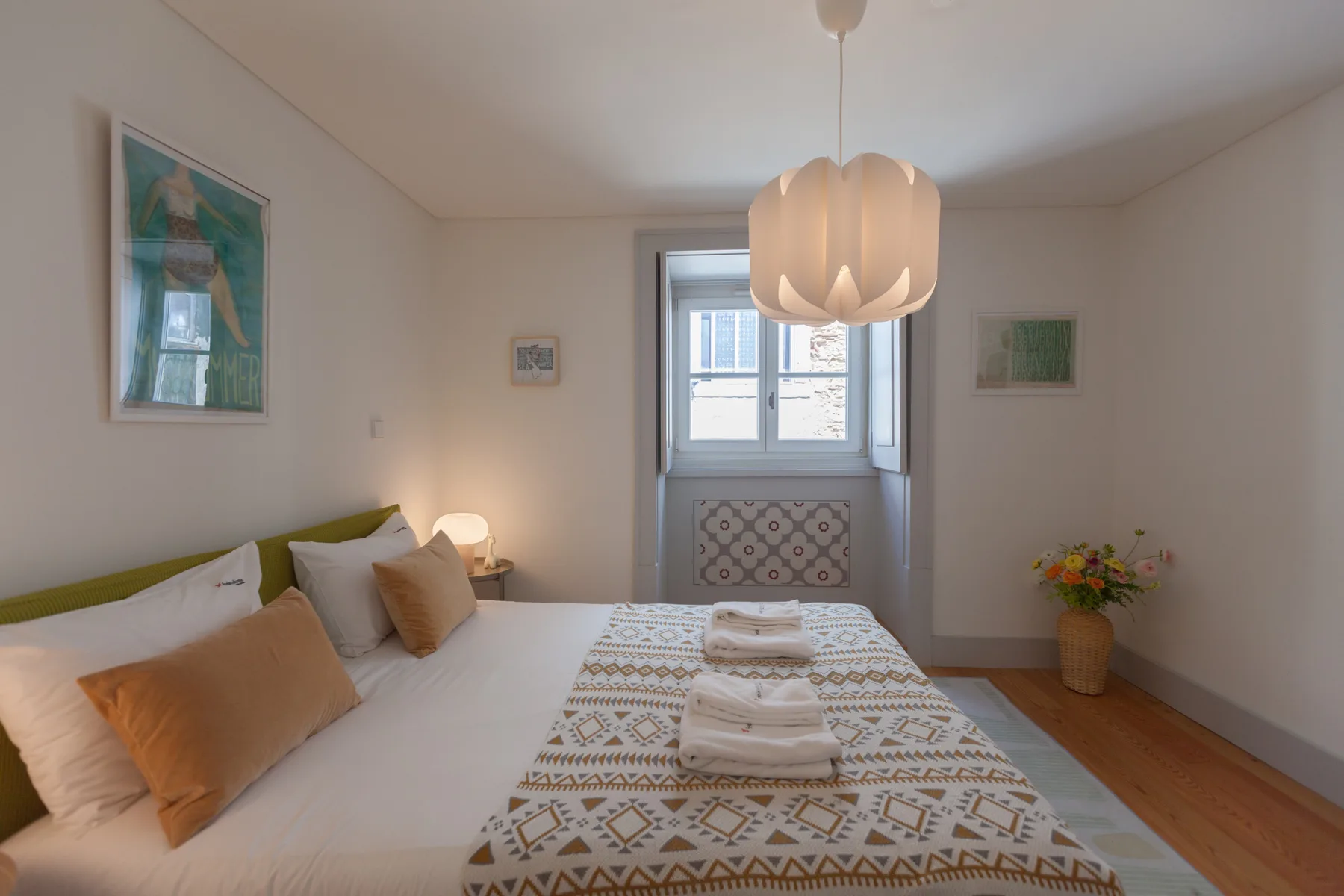 A bedroom with a bed, patterned bedding, and a window.