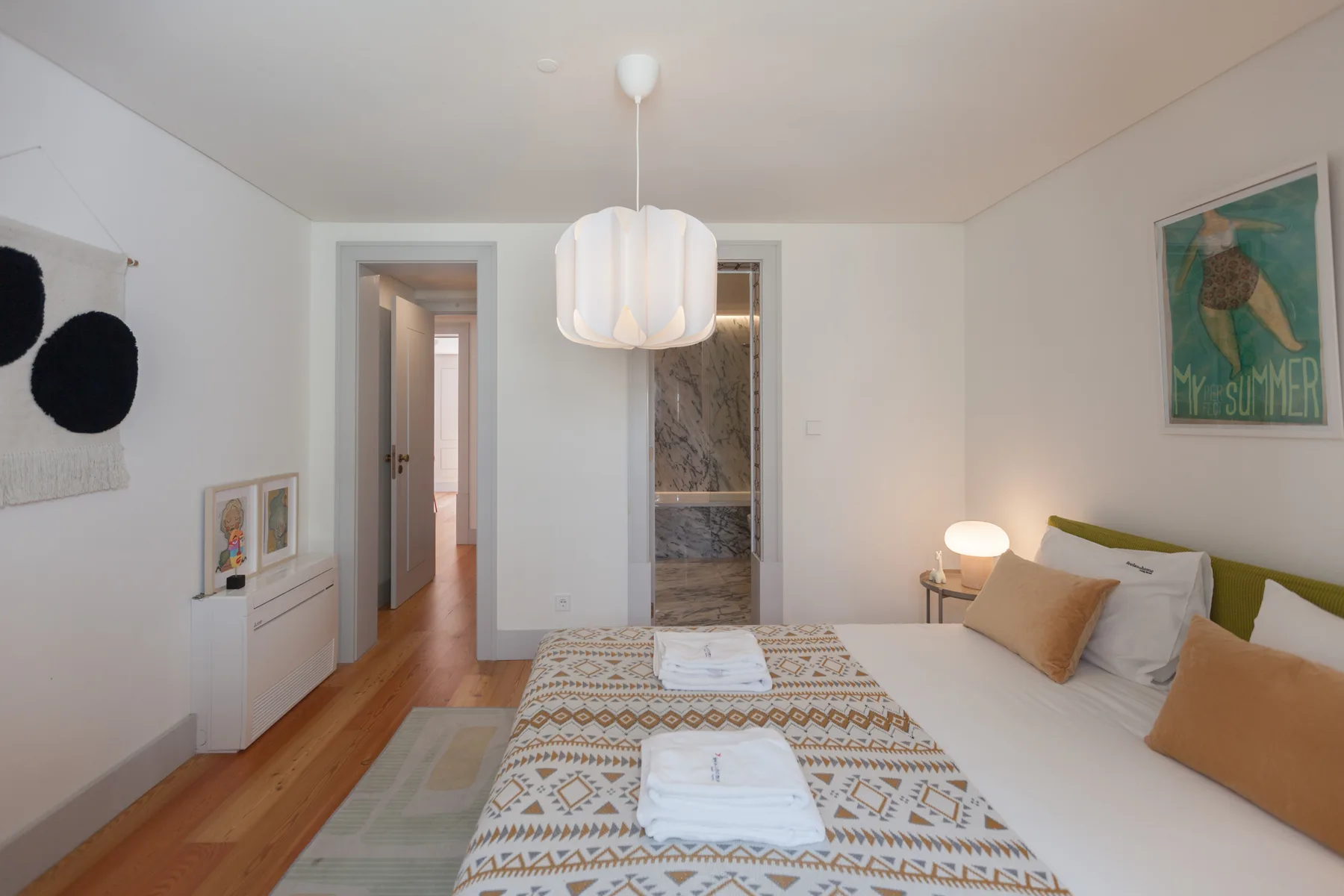A bedroom with a bed, patterned runner, and open doorway to a bathroom.