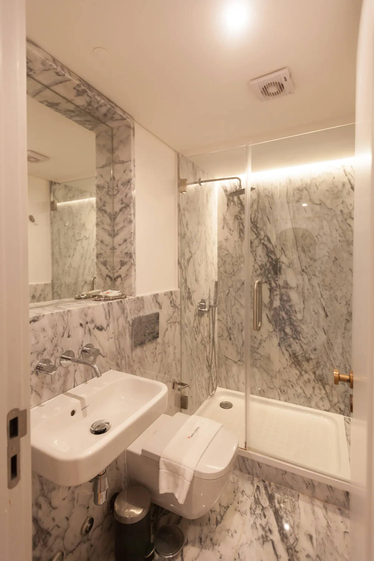 A marble-finished bathroom with a sink, toilet, and bathtub.