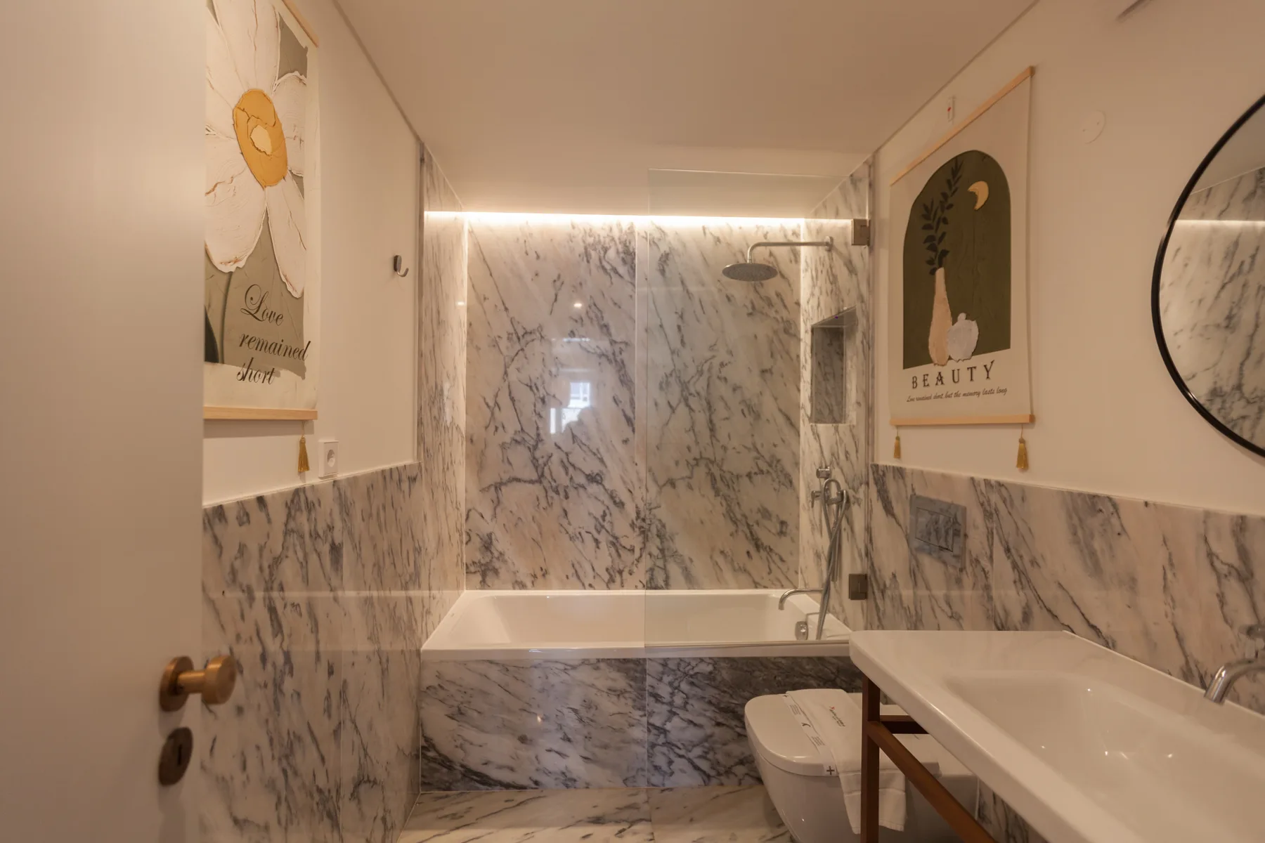 A marble bathroom with a bathtub, toilet, and sink.