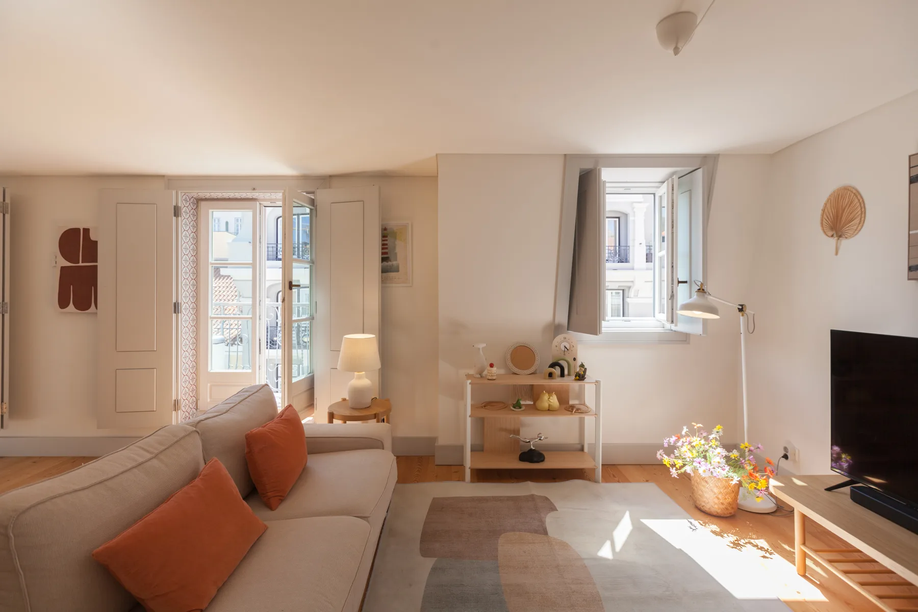 A bright living room with seating, a coffee table, and tall windows.