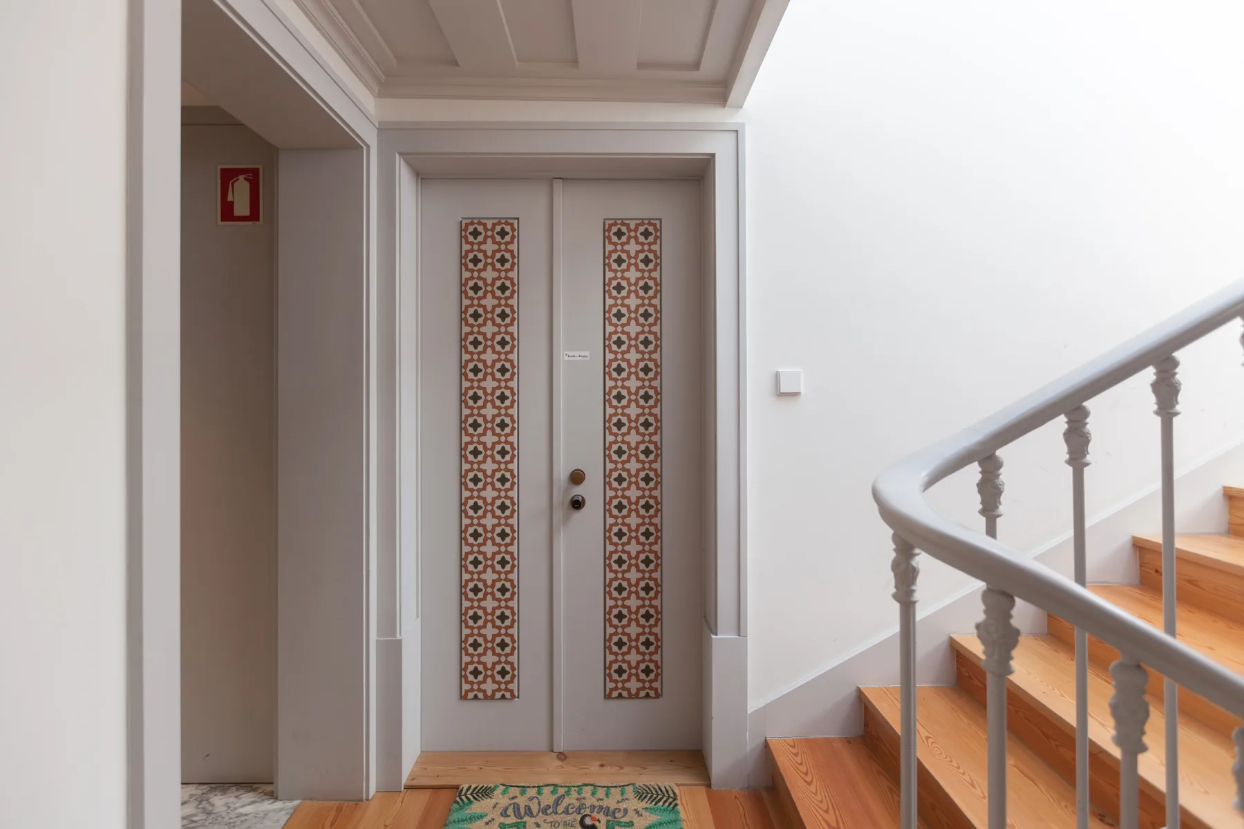 An interior hallway with patterned double doors and a staircase.