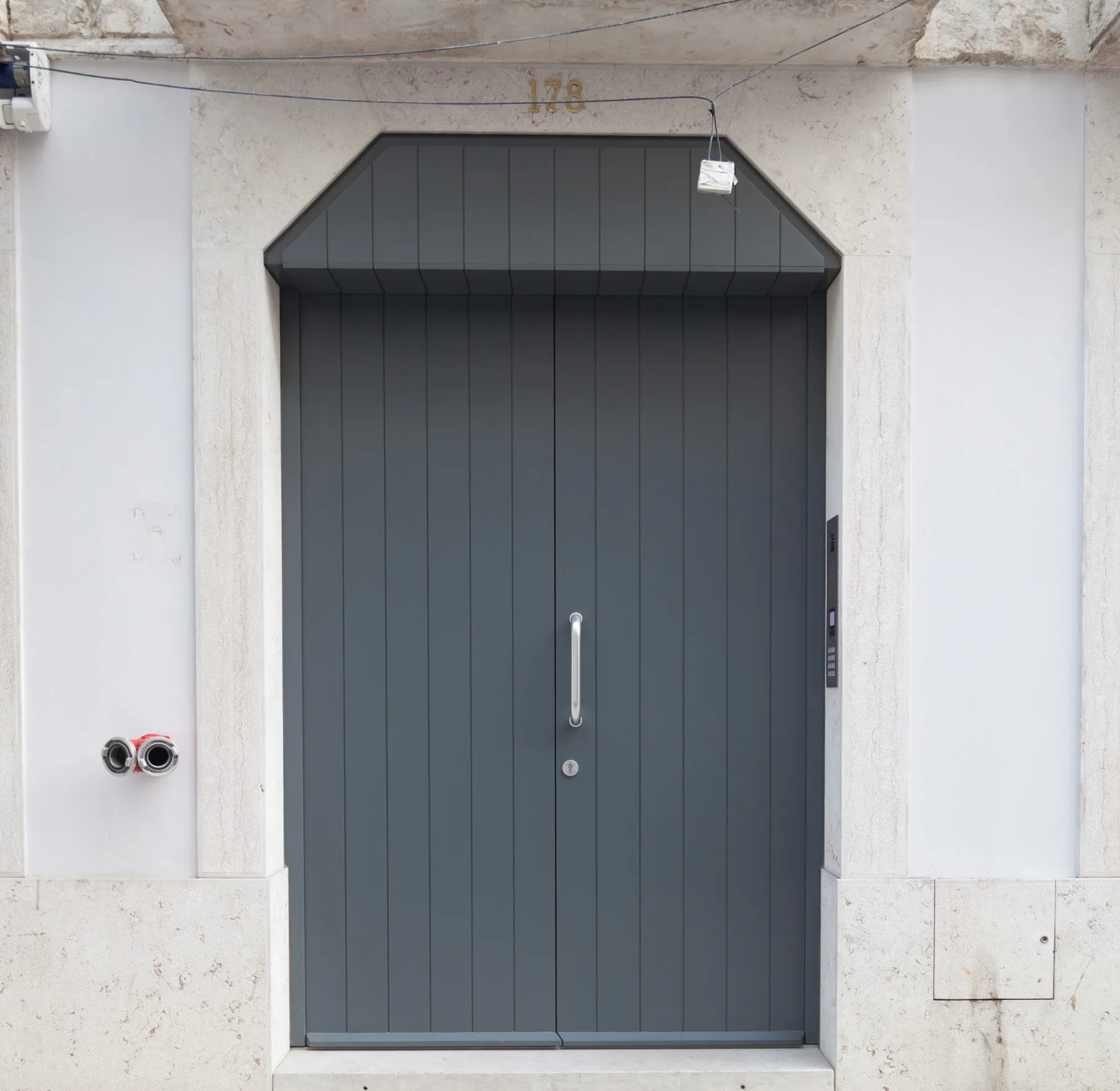 A dark gray entrance door set in a light stone facade.