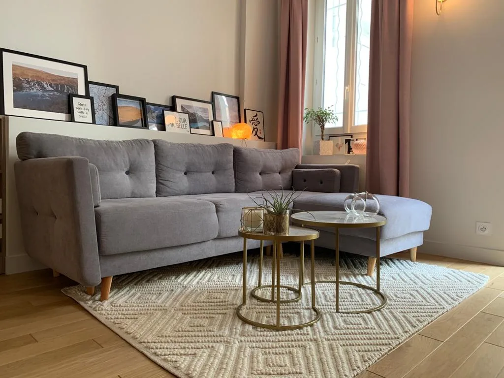 A living room with gray seating, a textured rug, and small tables.