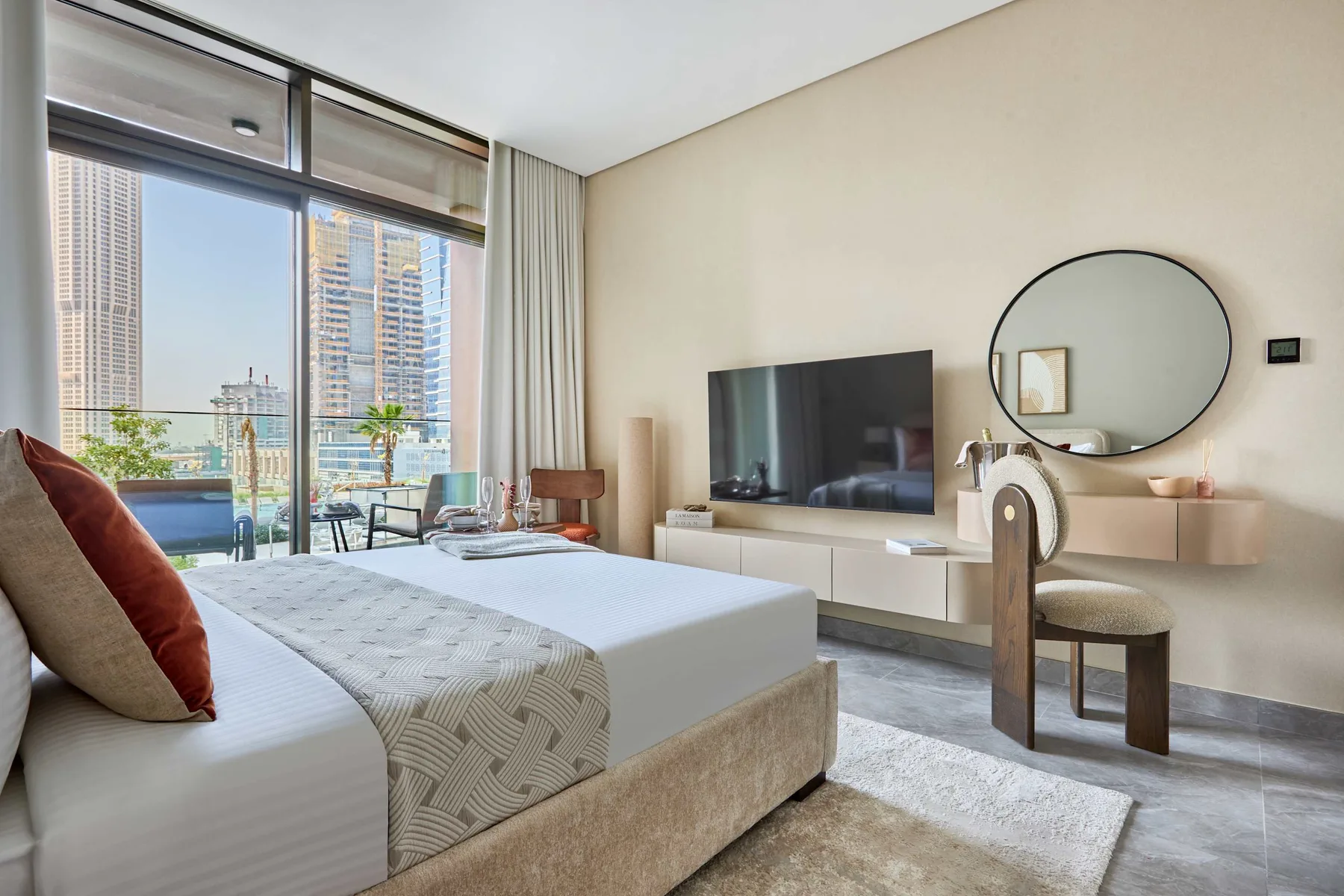 Un dormitorio luminoso con una cama grande, televisor y ventanales.