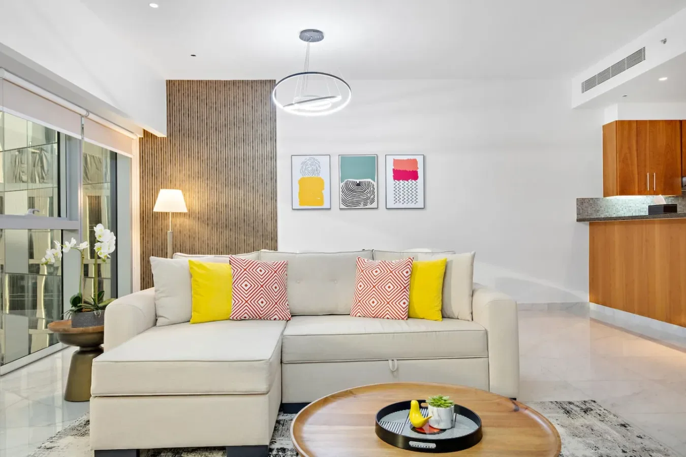 Una sala luminosa con un sofá seccional y cuadros enmarcados.