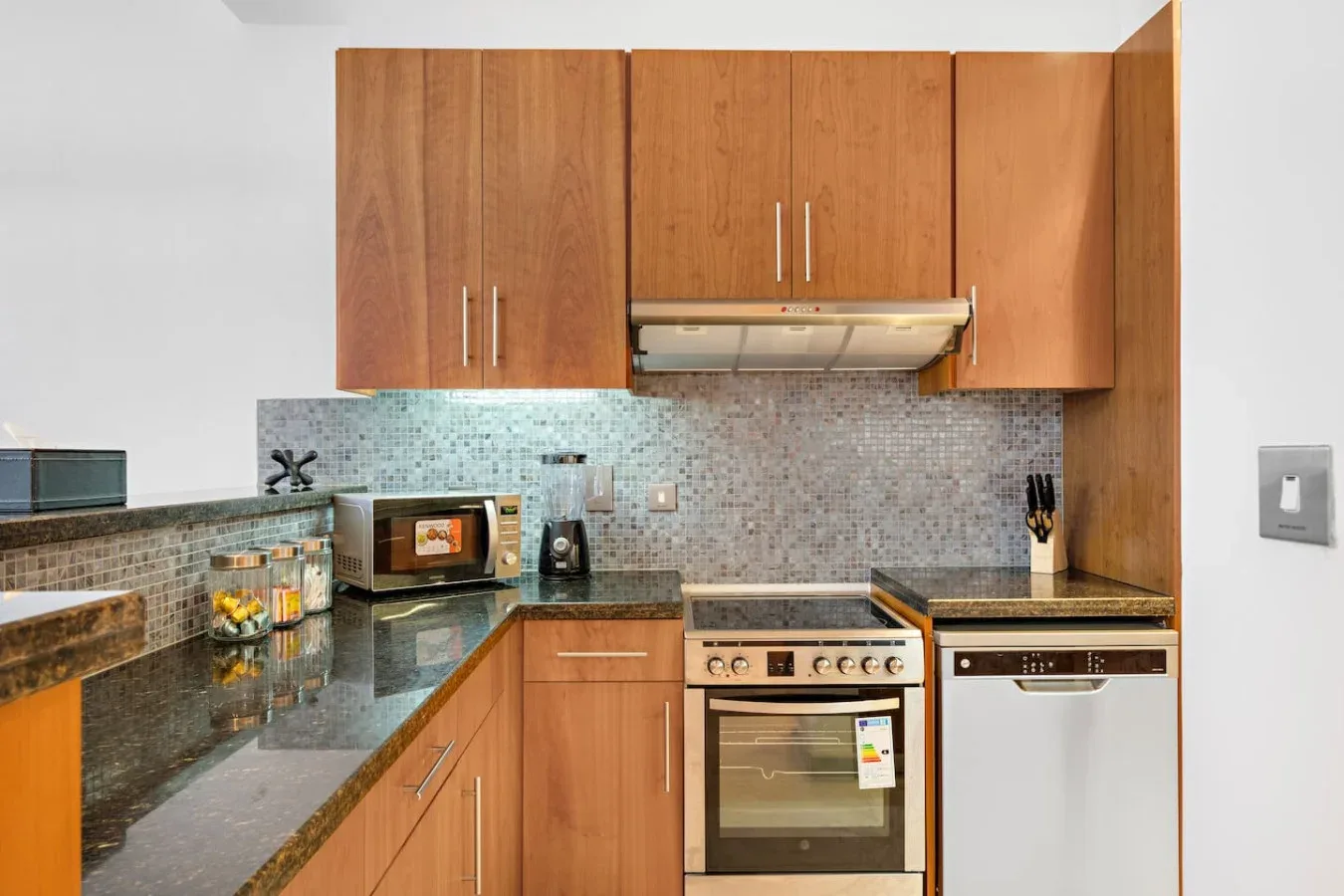 Una cocina con gabinetes de madera, encimeras oscuras y horno empotrado.