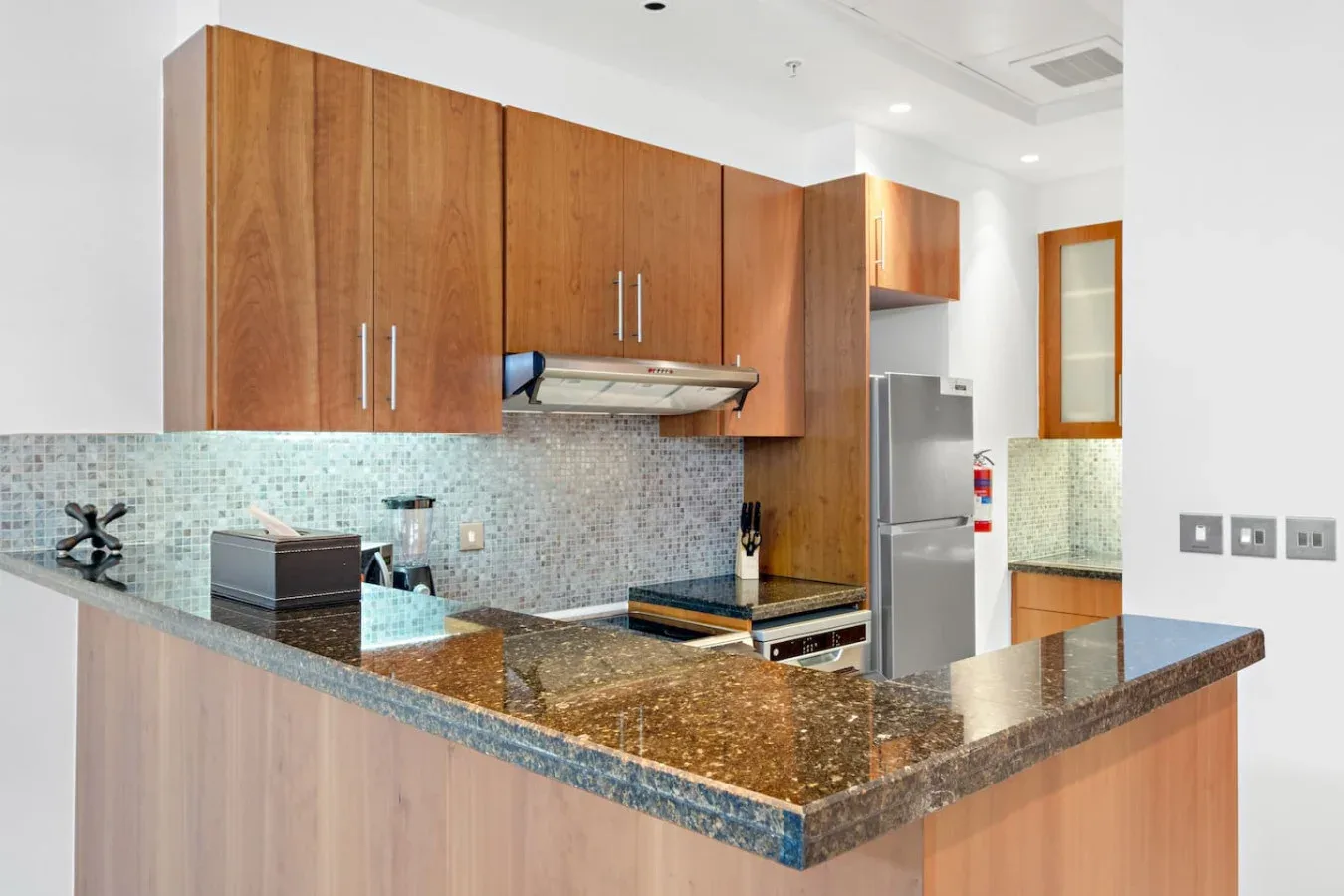 Una cocina moderna con gabinetes de madera, un salpicadero de azulejos y una encimera de piedra.