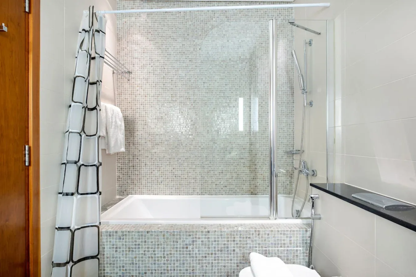 Un baño revestido de azulejos con bañera y mampara de ducha de vidrio.