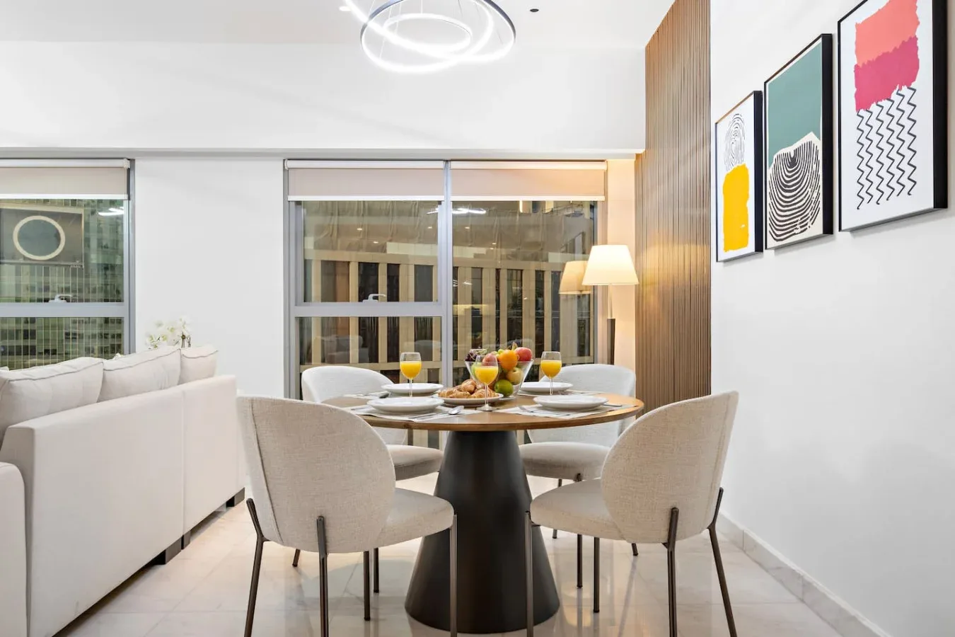Comedor con una mesa redonda, asientos tapizados y cuadros en la pared.