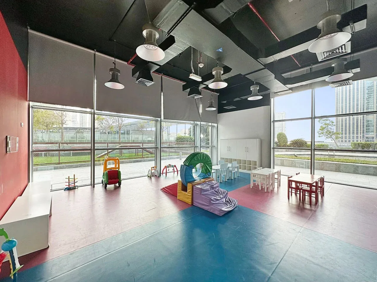 Una luminosa sala de juegos interior con equipo colorido y grandes ventanales.