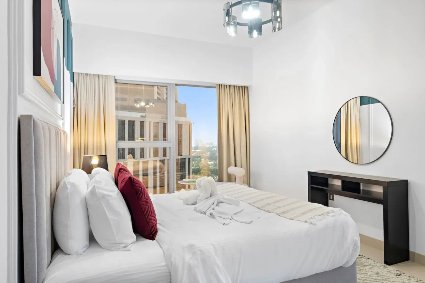 Un dormitorio con una cama bien tendida y ventanales junto a cortinas beige.