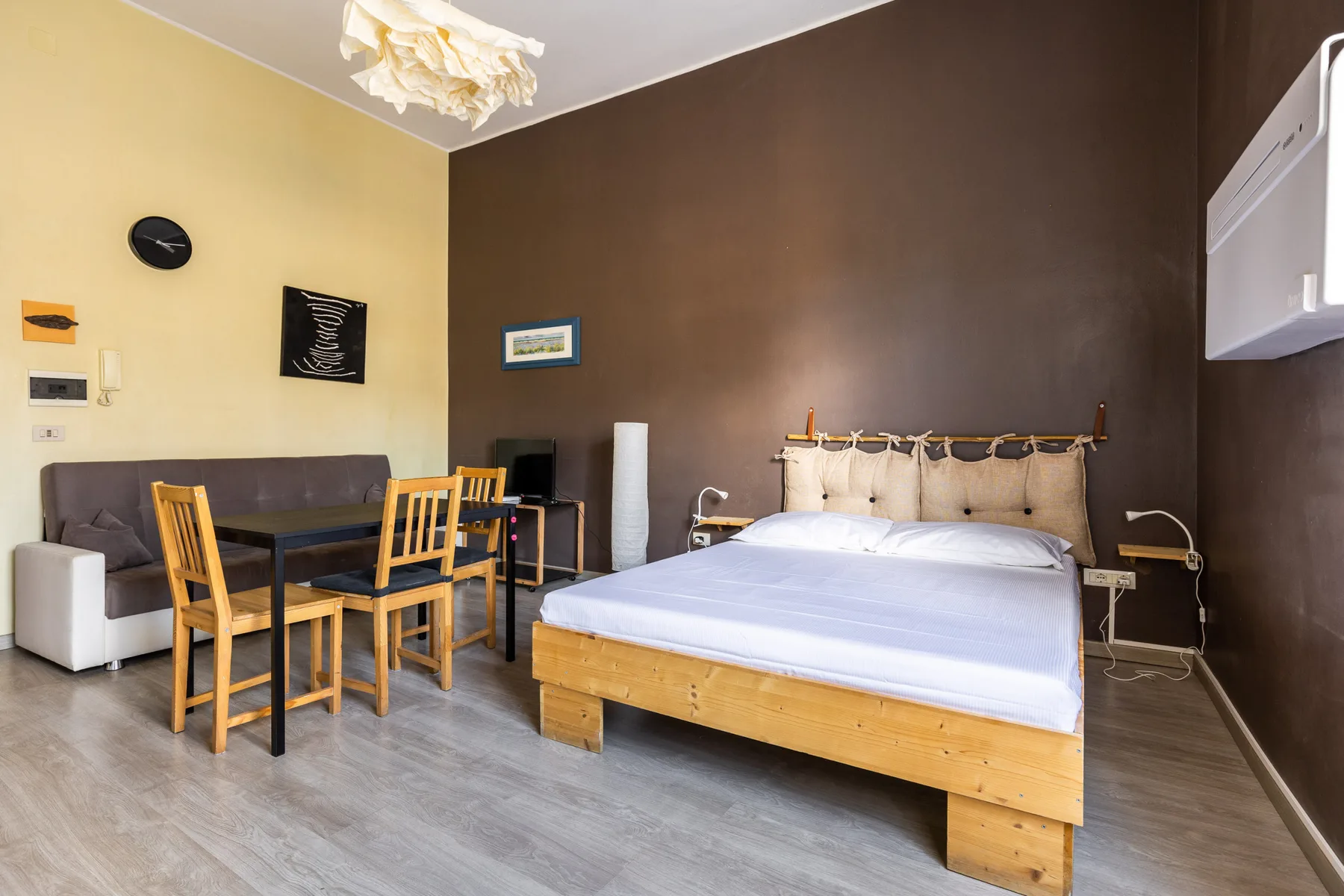 A bedroom with a bed, a small dining table, and chairs.